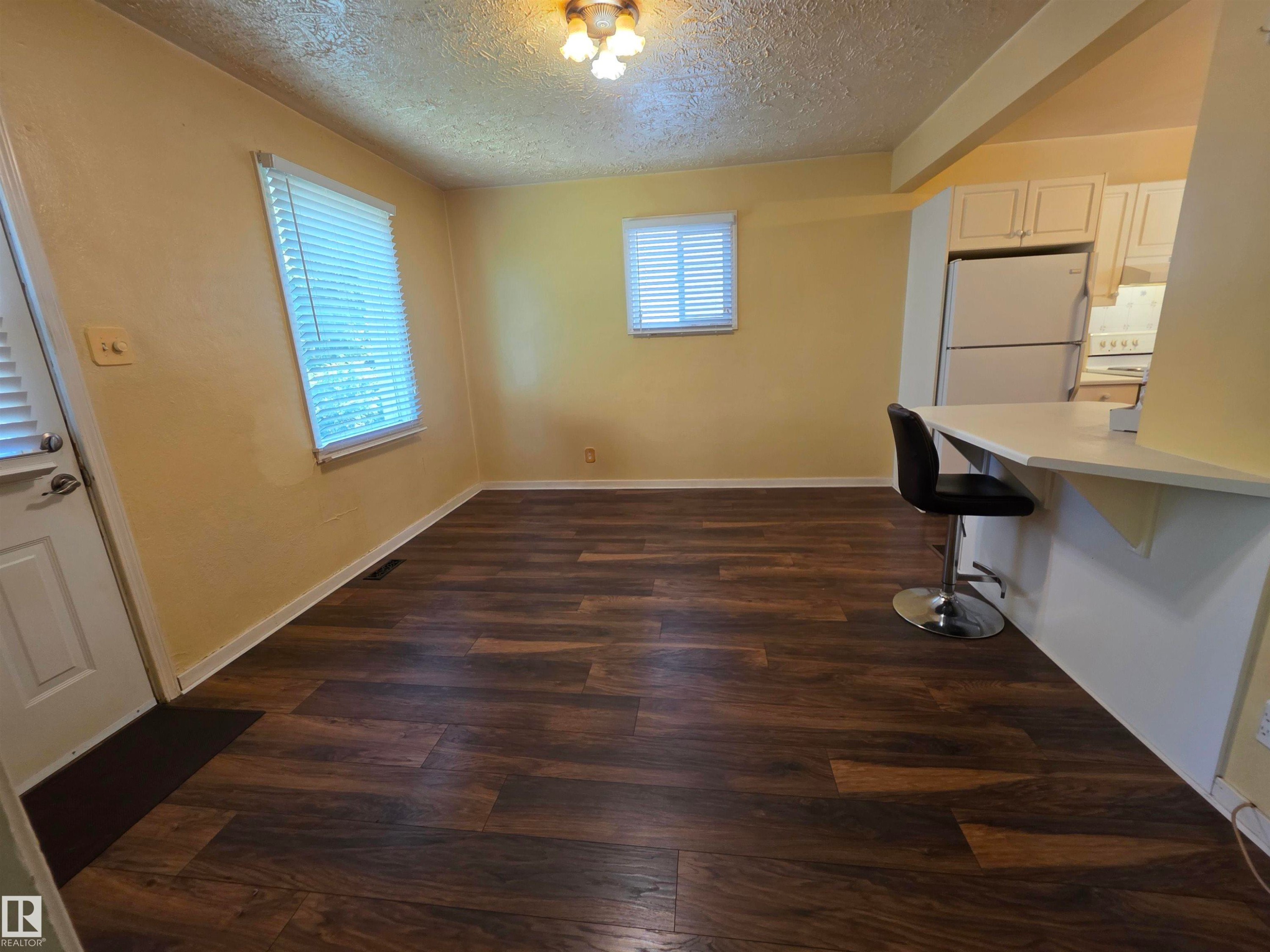 Wood-finish flooring throughout, multiple windows with blinds, and a breakfast bar - 10438 147 Street Nw, Edmonton, AB