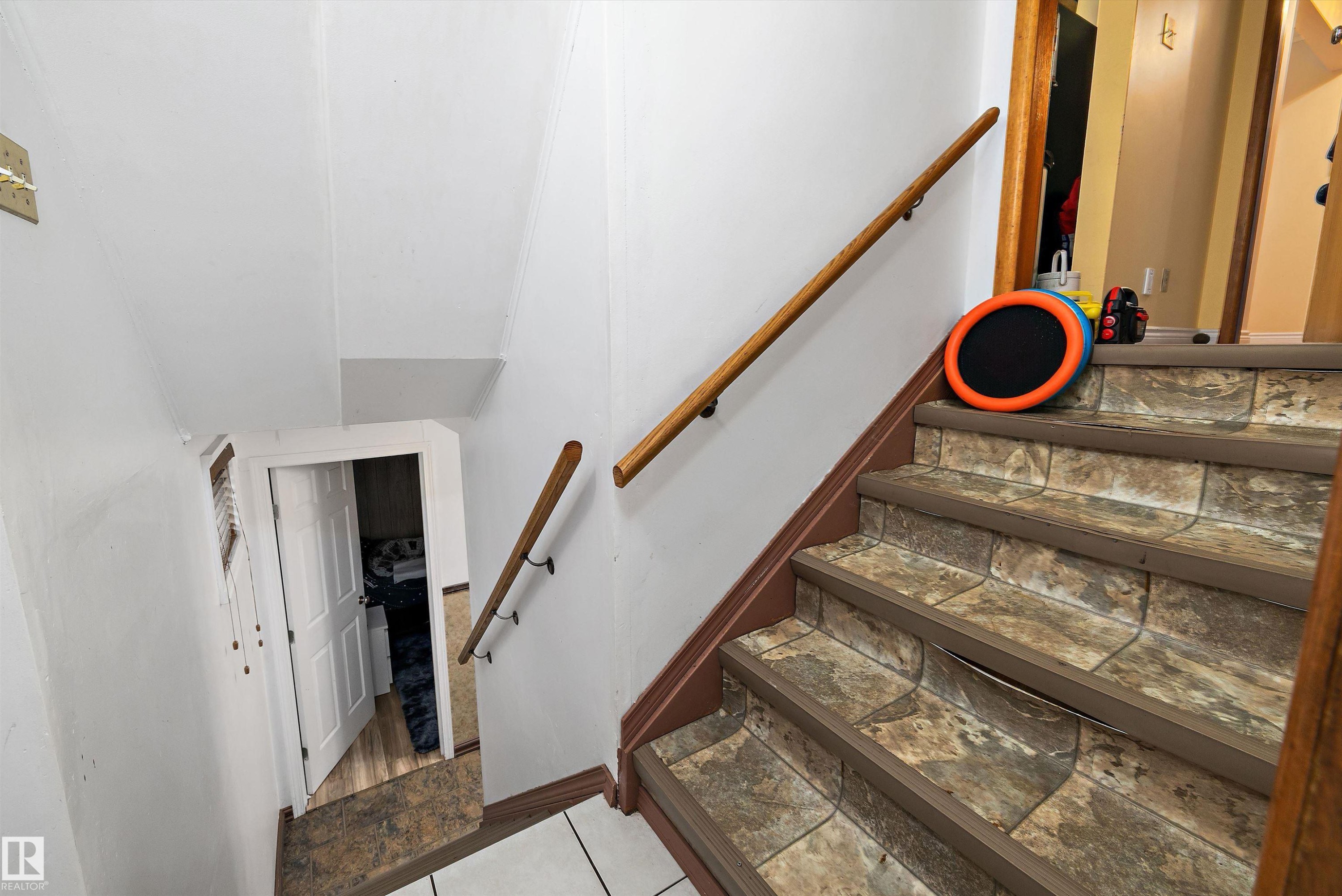 Staircase featuring wood-finish handrails and stone-look stair treads - 10621 60A Avenue Nw, Edmonton, AB
