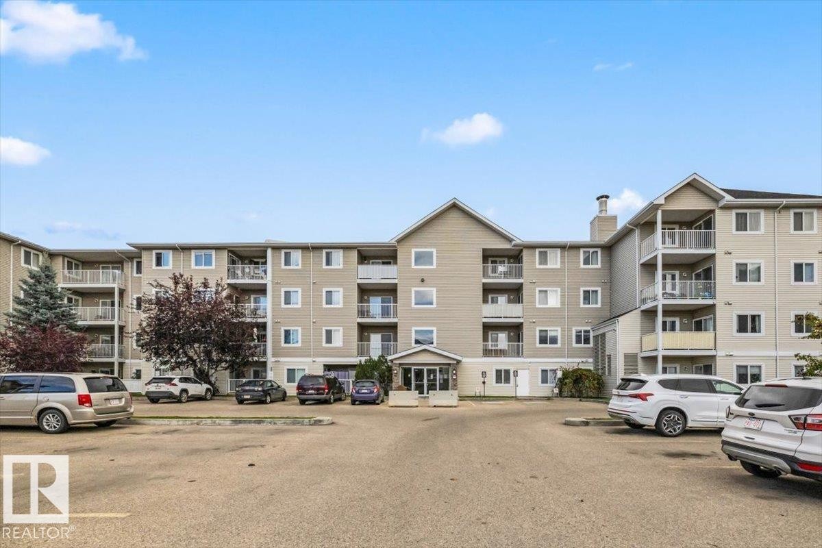 Multi-story residential building featuring balconies, multiple windows, a central entrance, and an external chimney - #110 4309 33 St, Stony Plain, AB