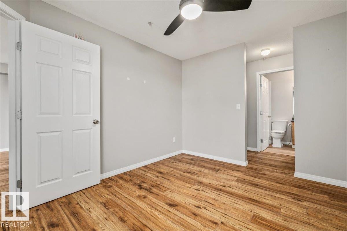 Wood-finish flooring, light gray wall paint, and white trim - #110 4309 33 St, Stony Plain, AB