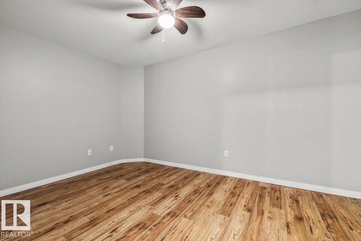Light gray wall paint, wood-finish flooring, white trim, and a ceiling fan with integrated lighting - #110 4309 33 St, Stony Plain, AB