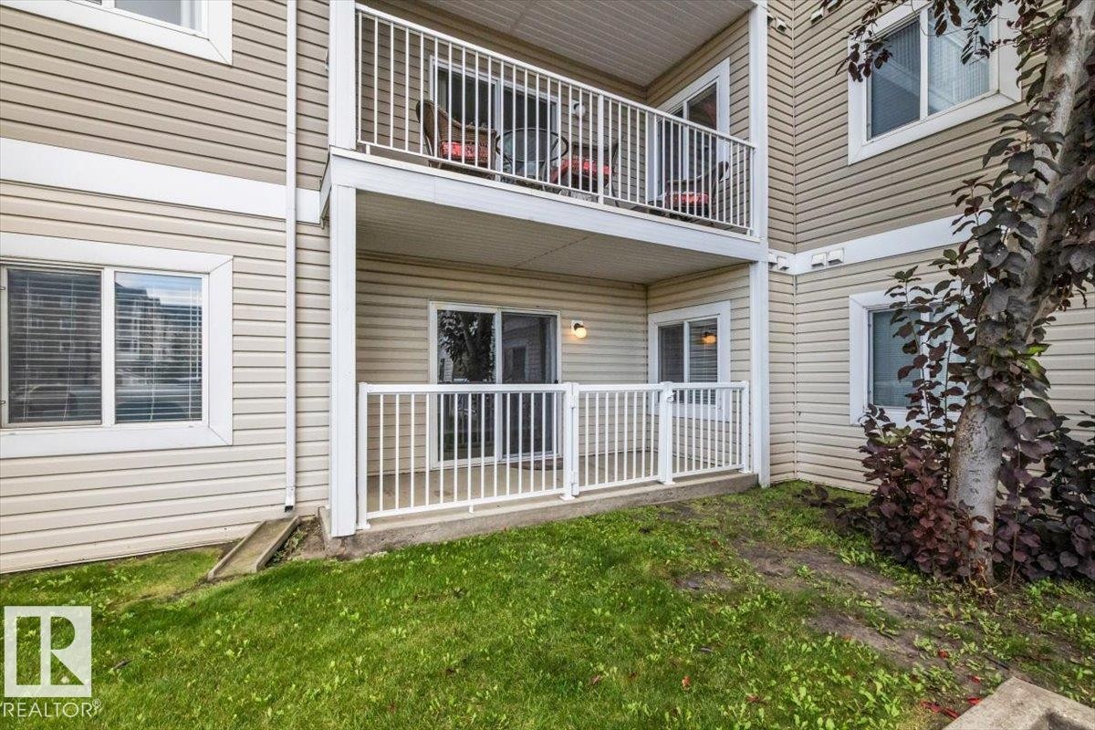 Multi-level residence featuring expansive tiered decking with white railings, manicured lawn, and mature landscaping including climbing ivy - #110 4309 33 St, Stony Plain, AB