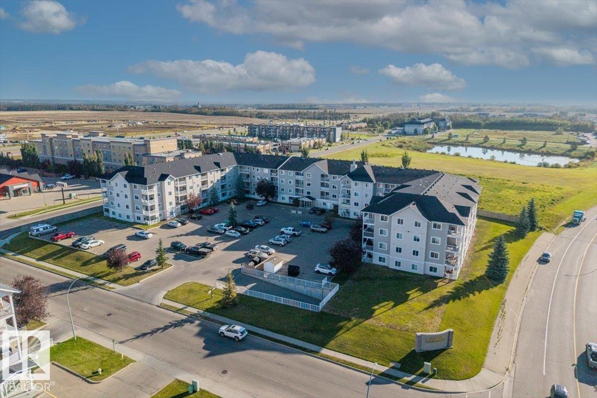 Multi-story residential complex featuring light grey siding and dark pitched roofs - #110 4309 33 St, Stony Plain, AB