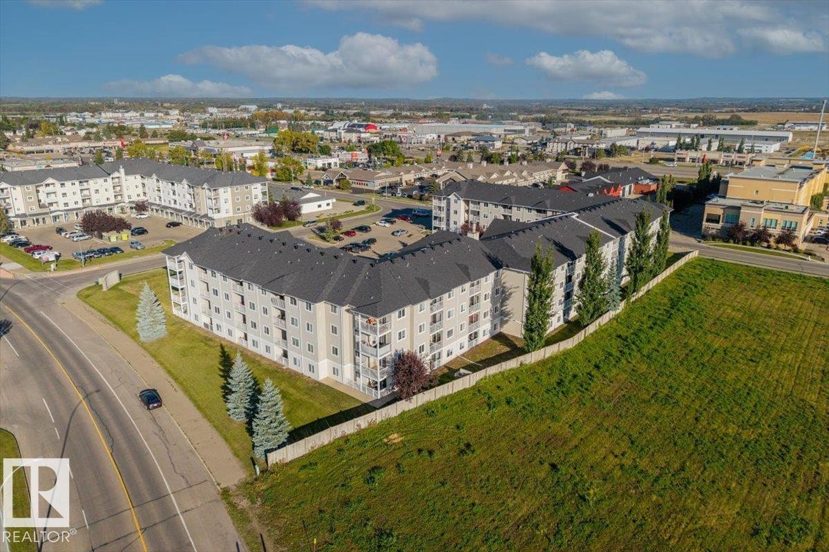 Multi-story residential buildings with dark shingle roofs and light-colored siding - #110 4309 33 St, Stony Plain, AB