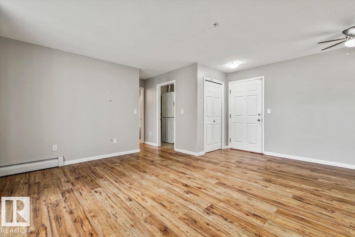 Open living area featuring wood-finish flooring, light gray wall paint, and a ceiling fan with integrated lighting - #110 4309 33 St, Stony Plain, AB