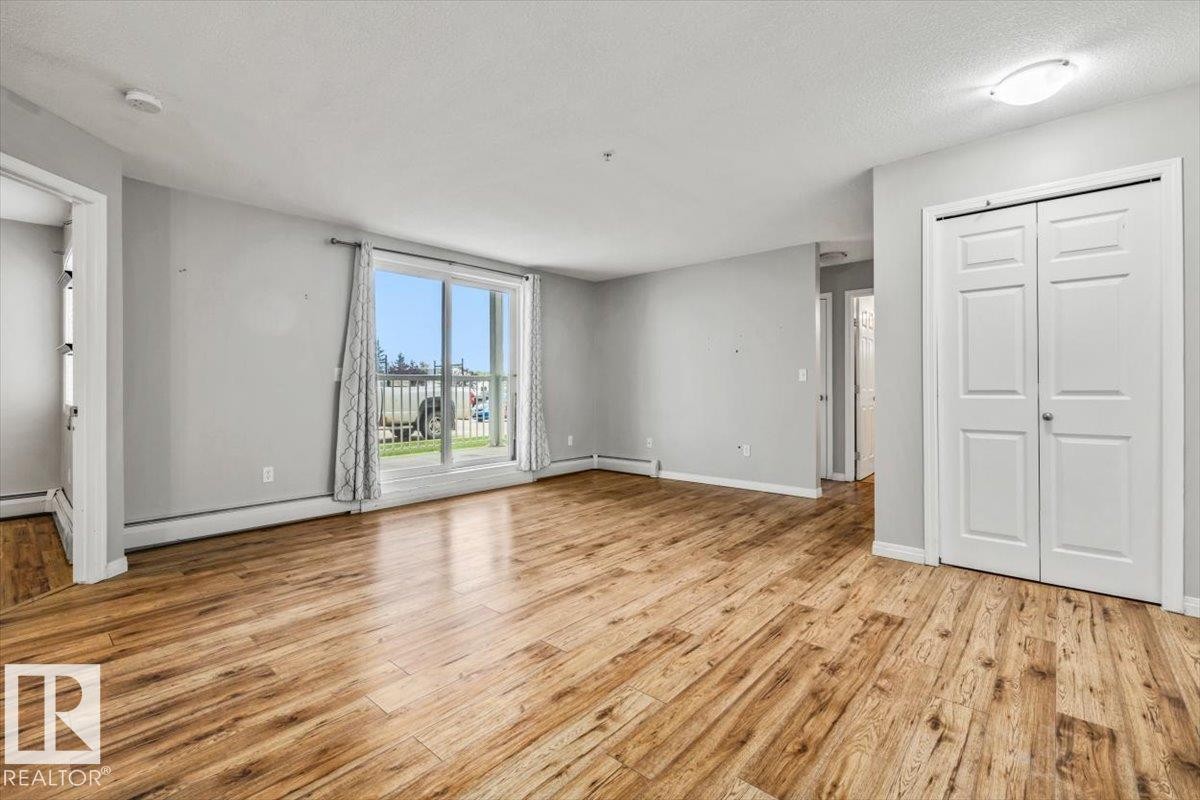 Wood-finish flooring throughout, sliding glass door, white bi-fold closet doors, and recessed ceiling lighting - #110 4309 33 St, Stony Plain, AB