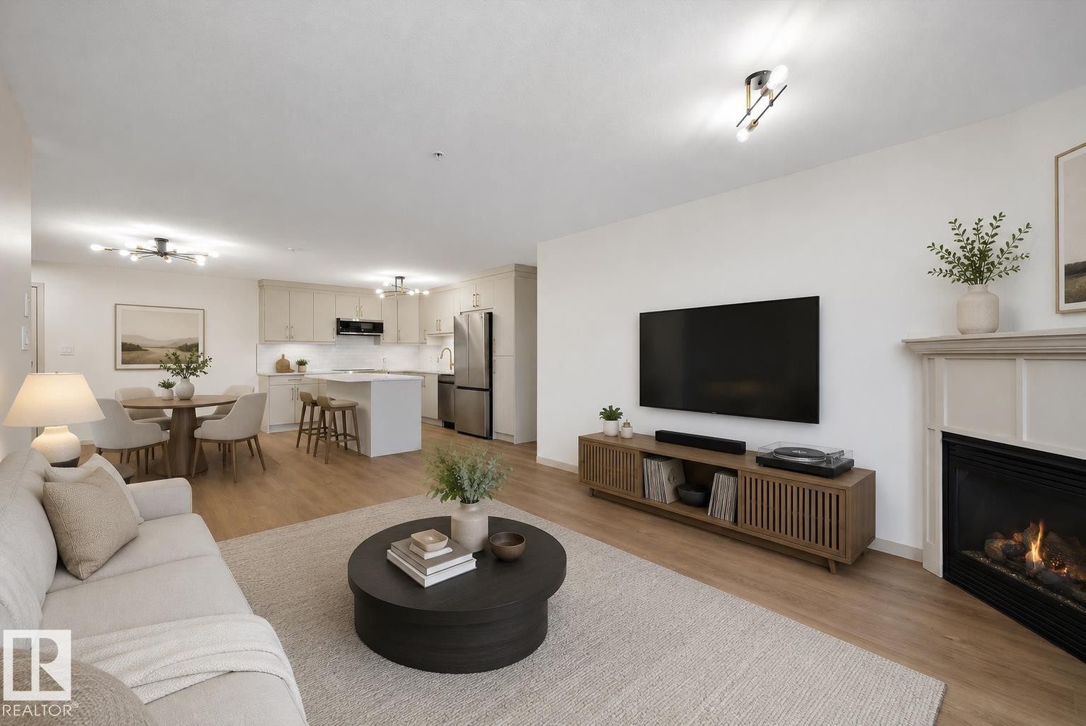 Living area featuring wood-finish flooring, a corner fireplace with a traditional mantel, and recessed ceiling lighting (virtually staged) - #353 2096 Blackmud Creek Dr Sw, Edmonton, AB - Indoor Photo Showing Living Room With Fireplace