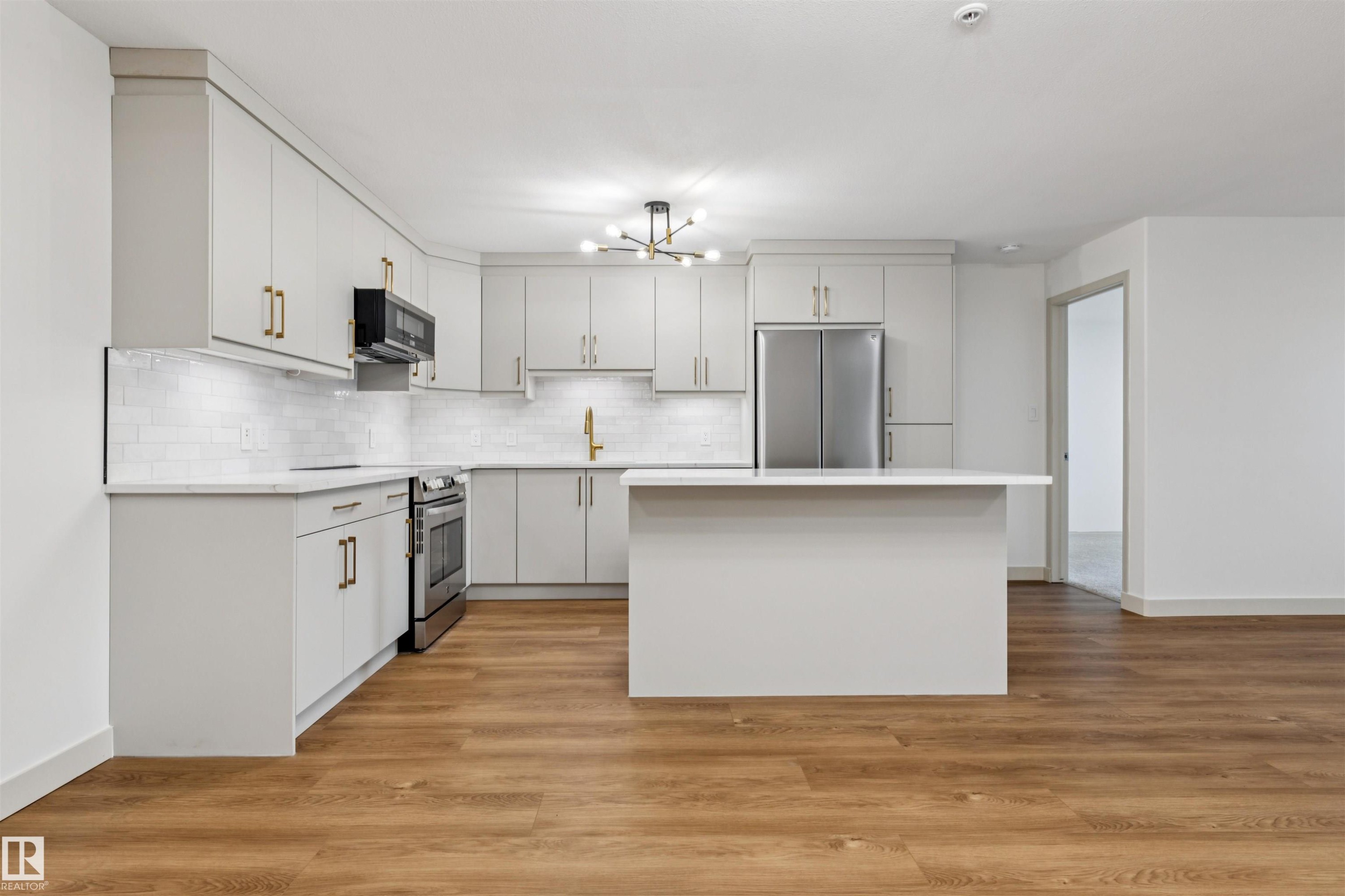 Modern kitchen featuring light gray cabinetry, stainless steel appliances, a white subway tile backsplash, and a central island - #353 2096 Blackmud Creek Dr Sw, Edmonton, AB - Indoor Photo Showing Kitchen With Upgraded Kitchen