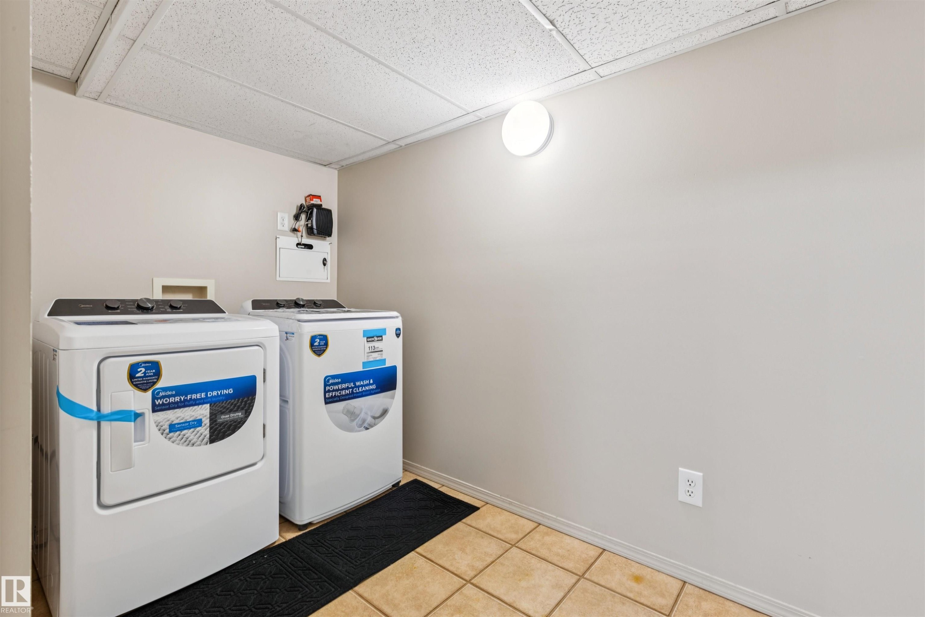 Dedicated laundry area featuring tile flooring, neutral wall paint, and a drop ceiling - #353 2096 Blackmud Creek Dr Sw, Edmonton, AB - Indoor Photo Showing Laundry Room