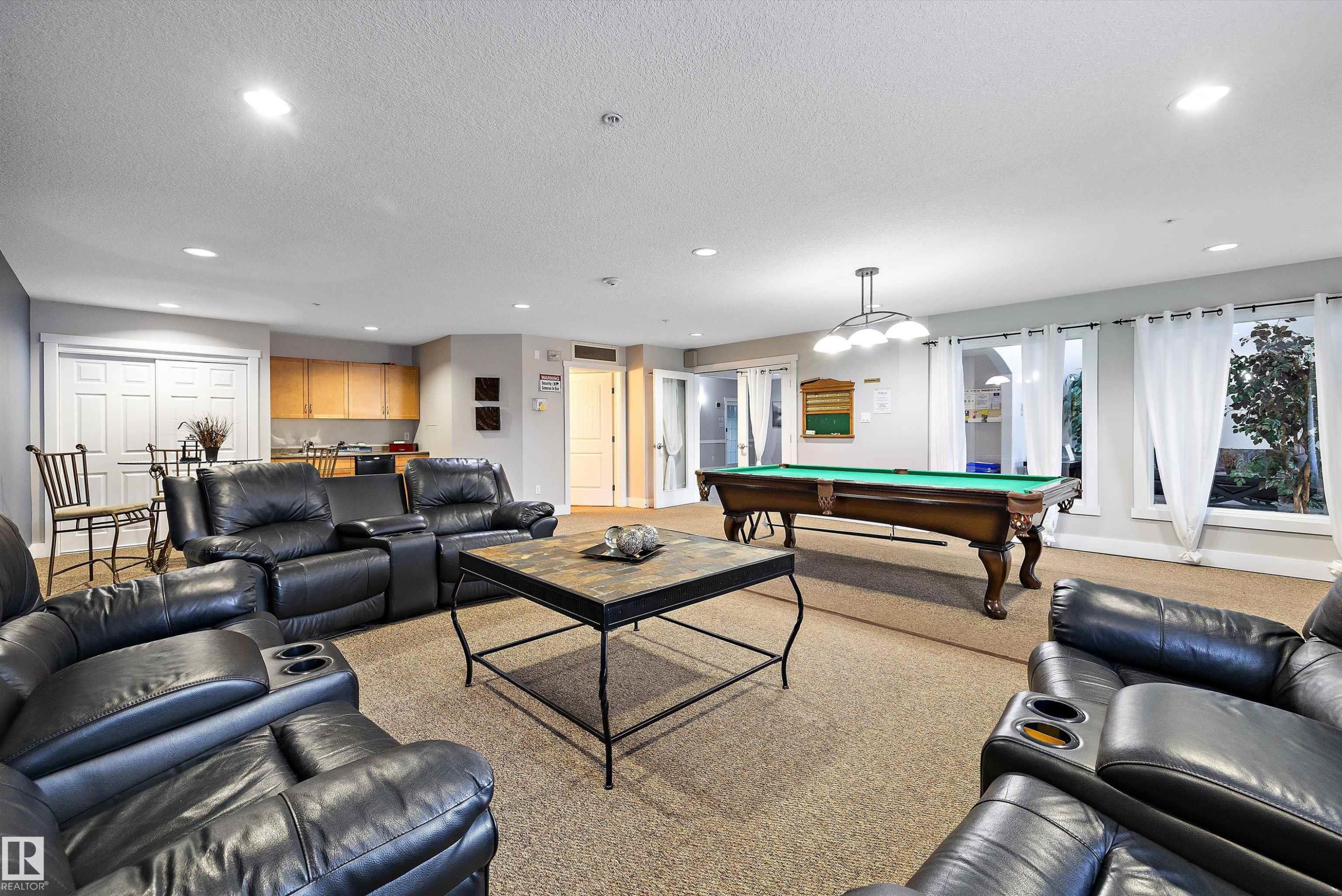 Spacious recreation area featuring a built-in wet bar with wood cabinetry, a billiards table, and multiple windows providing natural light - #353 2096 Blackmud Creek Dr Sw, Edmonton, AB - Indoor Photo Showing Other Room