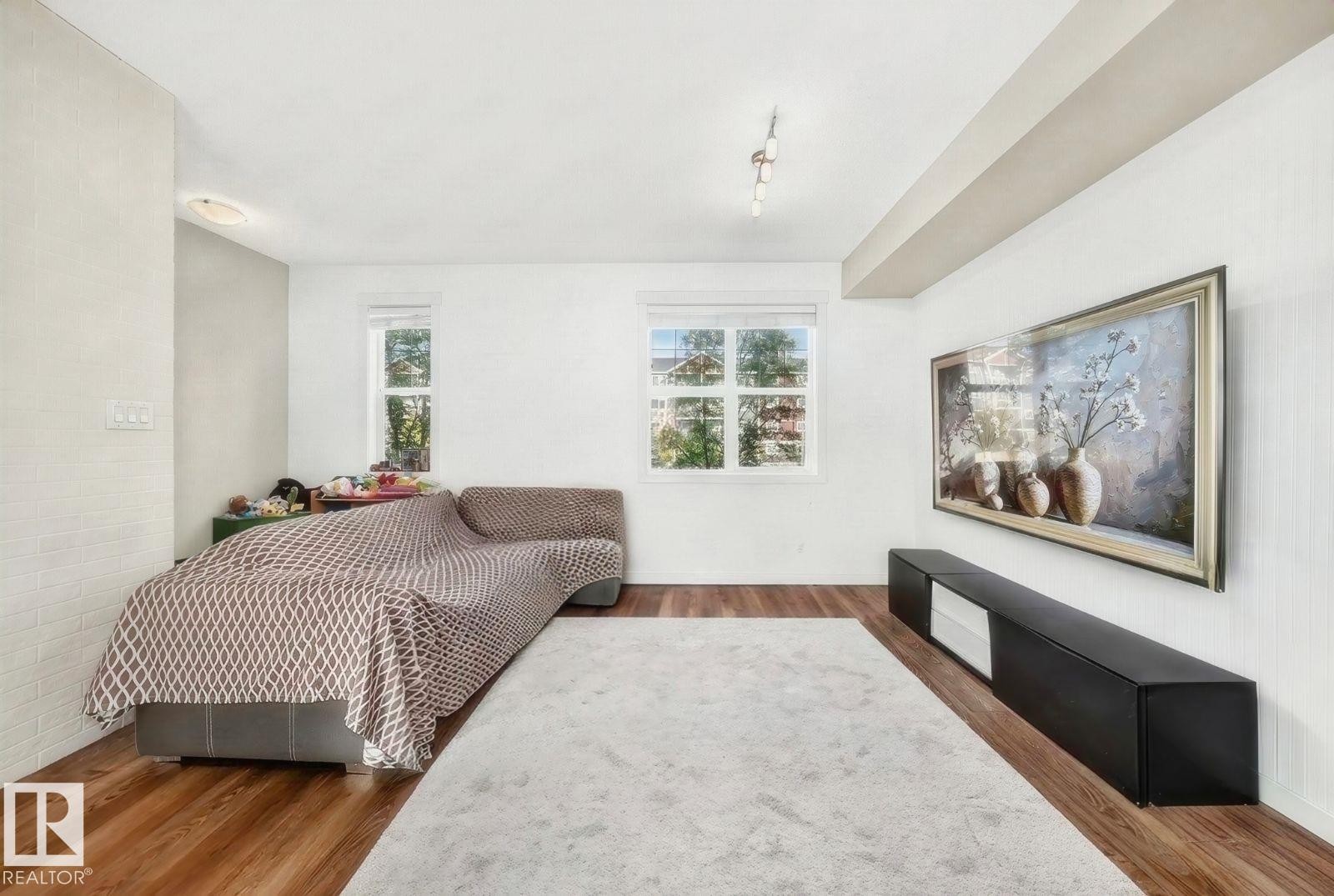 Hardwood-finish flooring, recessed lighting, track lighting, and two windows - #20 8315 180 Av Nw, Edmonton, AB