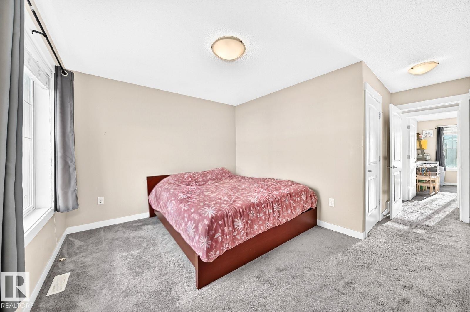 Neutral wall paint, light gray carpeting, a window with white trim, and flush mount lighting - #20 8315 180 Av Nw, Edmonton, AB