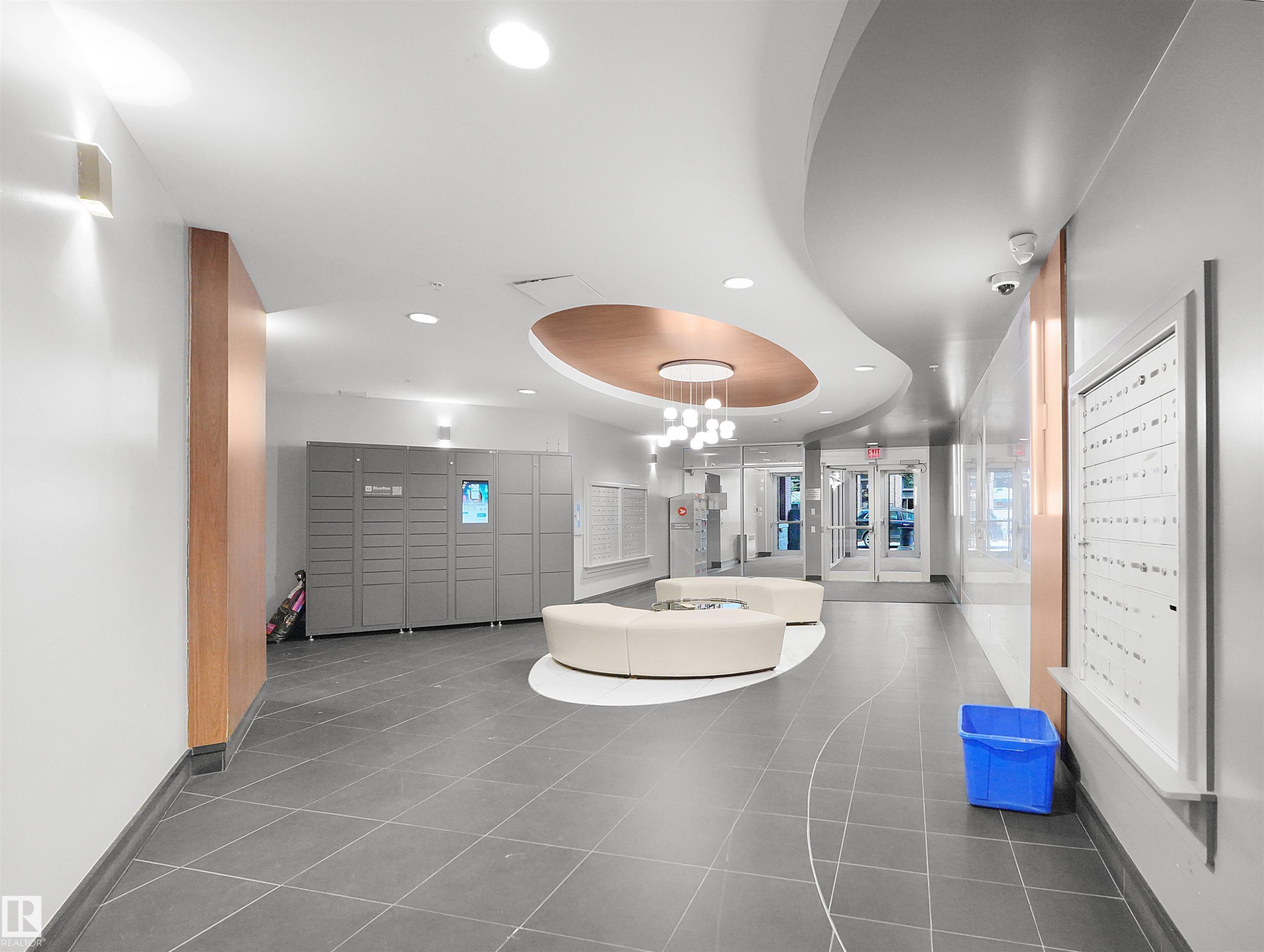 Lobby with gray large format tile flooring, curved white and copper ceiling design, and a modern chandelier - #1601 10136 104 St Nw, Edmonton, AB