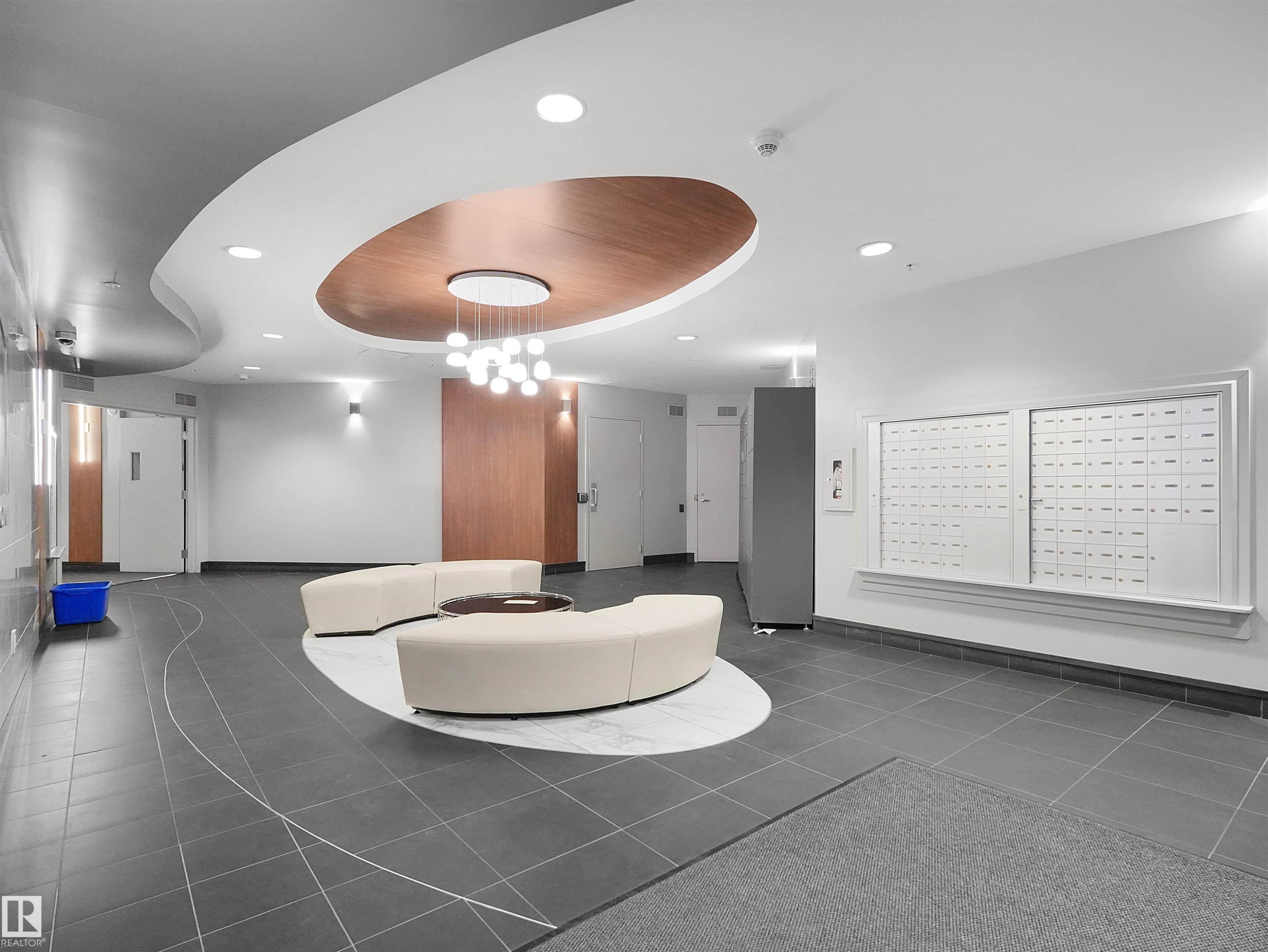 Curved ceiling design with wood-finish accent paneling, recessed lighting, and a contemporary chandelier - #1601 10136 104 St Nw, Edmonton, AB
