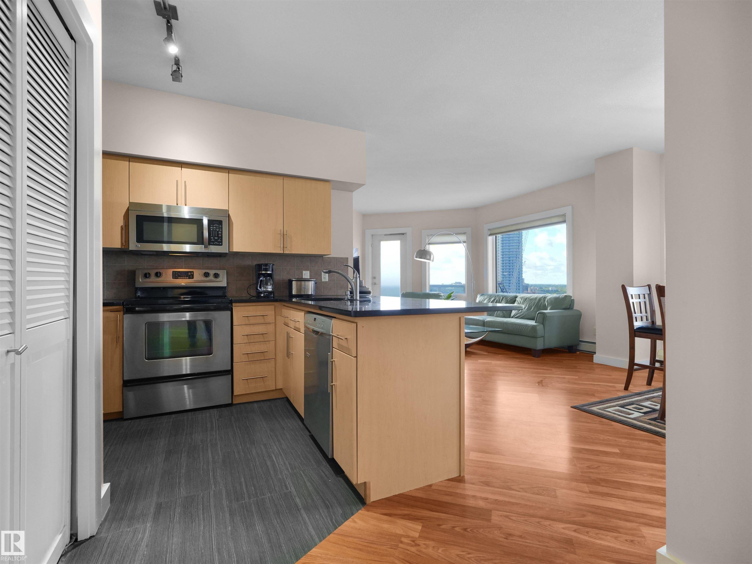 Kitchen featuring stainless steel appliances, wood-finish cabinetry, and dark countertops - #1601 10136 104 St Nw, Edmonton, AB