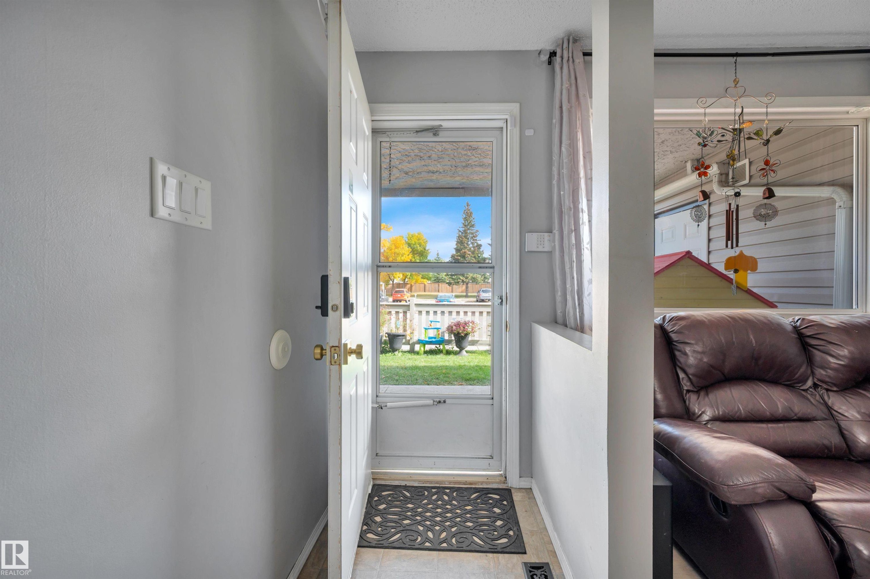 Entryway featuring a white door with a glass pane, light-toned walls, and wood-finish flooring - 15017 26 Street Nw, Edmonton, AB