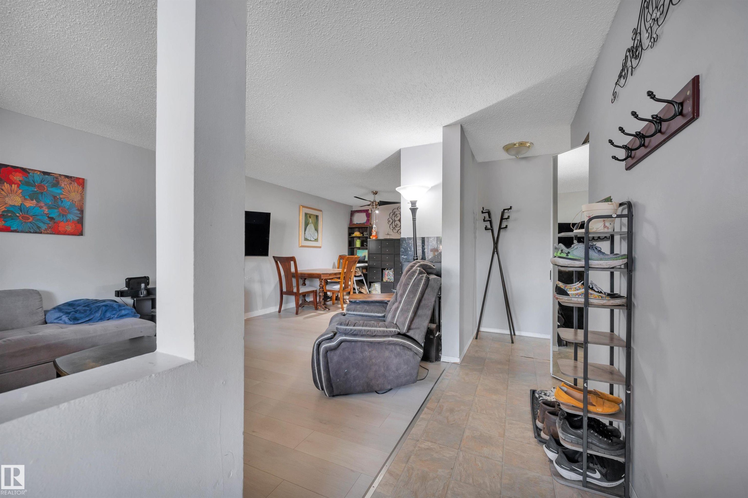 Open-concept living space with light gray wall paint and two distinct flooring types - 15017 26 Street Nw, Edmonton, AB
