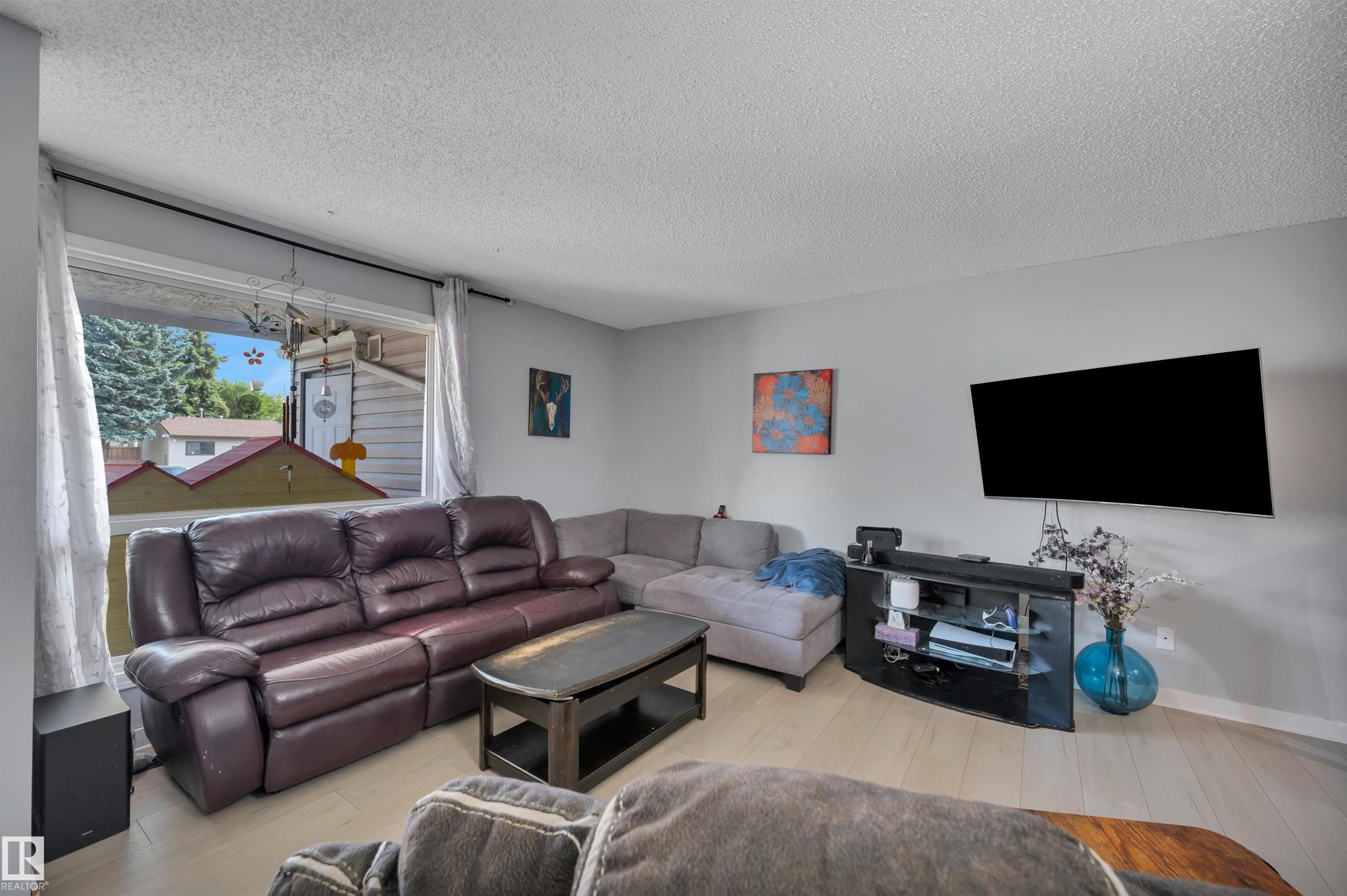 Living area featuring light wood-finish flooring and a large window - 15017 26 Street Nw, Edmonton, AB