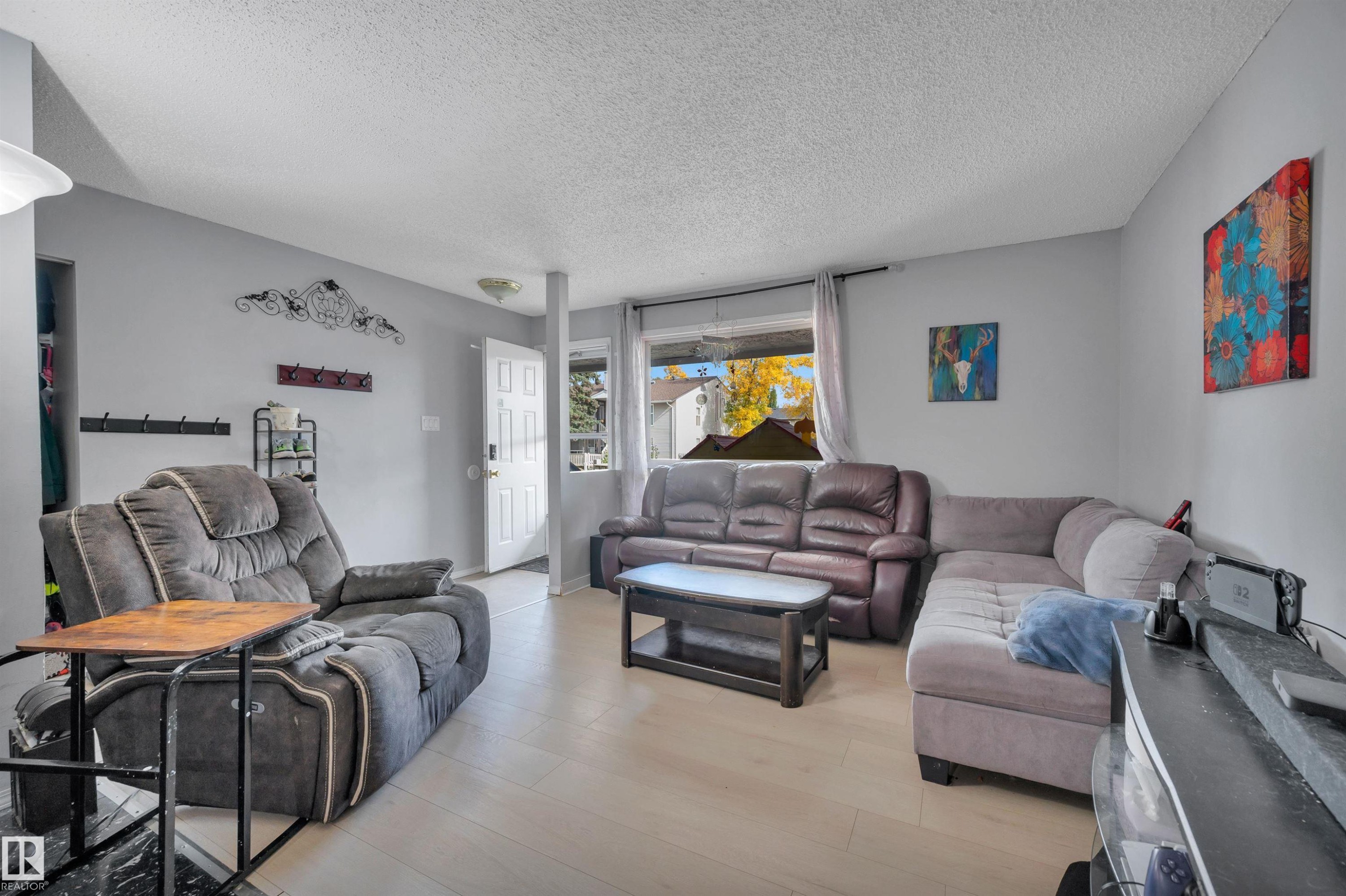 Light-toned wood-finish flooring, white paneled door, and a built-in storage niche - 15017 26 Street Nw, Edmonton, AB