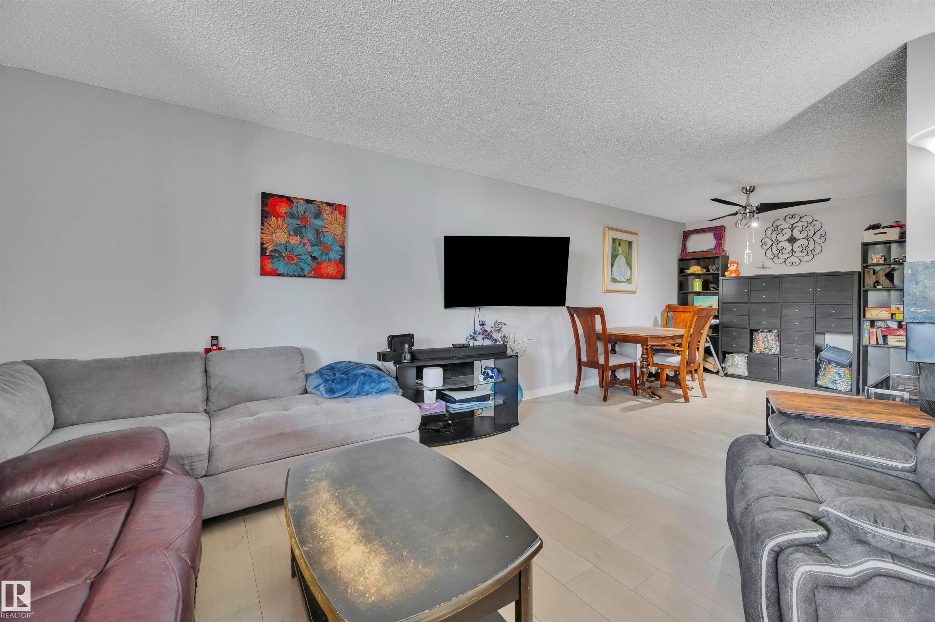 Open concept living space featuring light wood-finish flooring, a ceiling fan, and light gray walls - 15017 26 Street Nw, Edmonton, AB