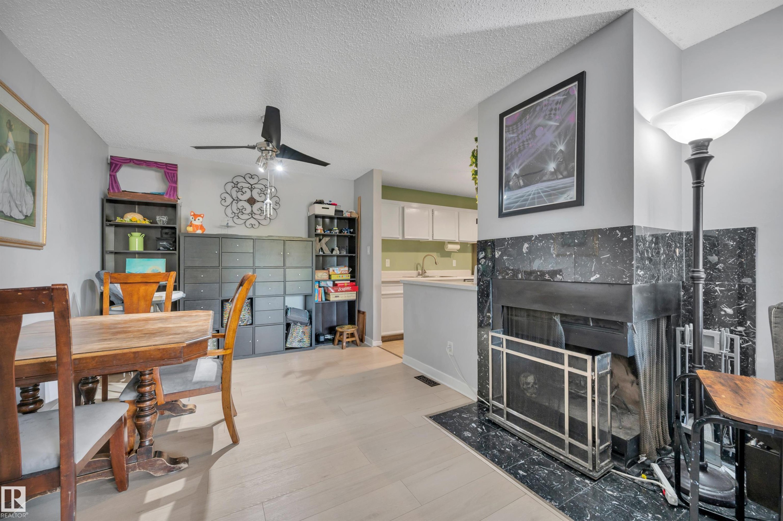 Wood-finish flooring, ceiling fan, and a fireplace with a dark stone surround and hearth - 15017 26 Street Nw, Edmonton, AB