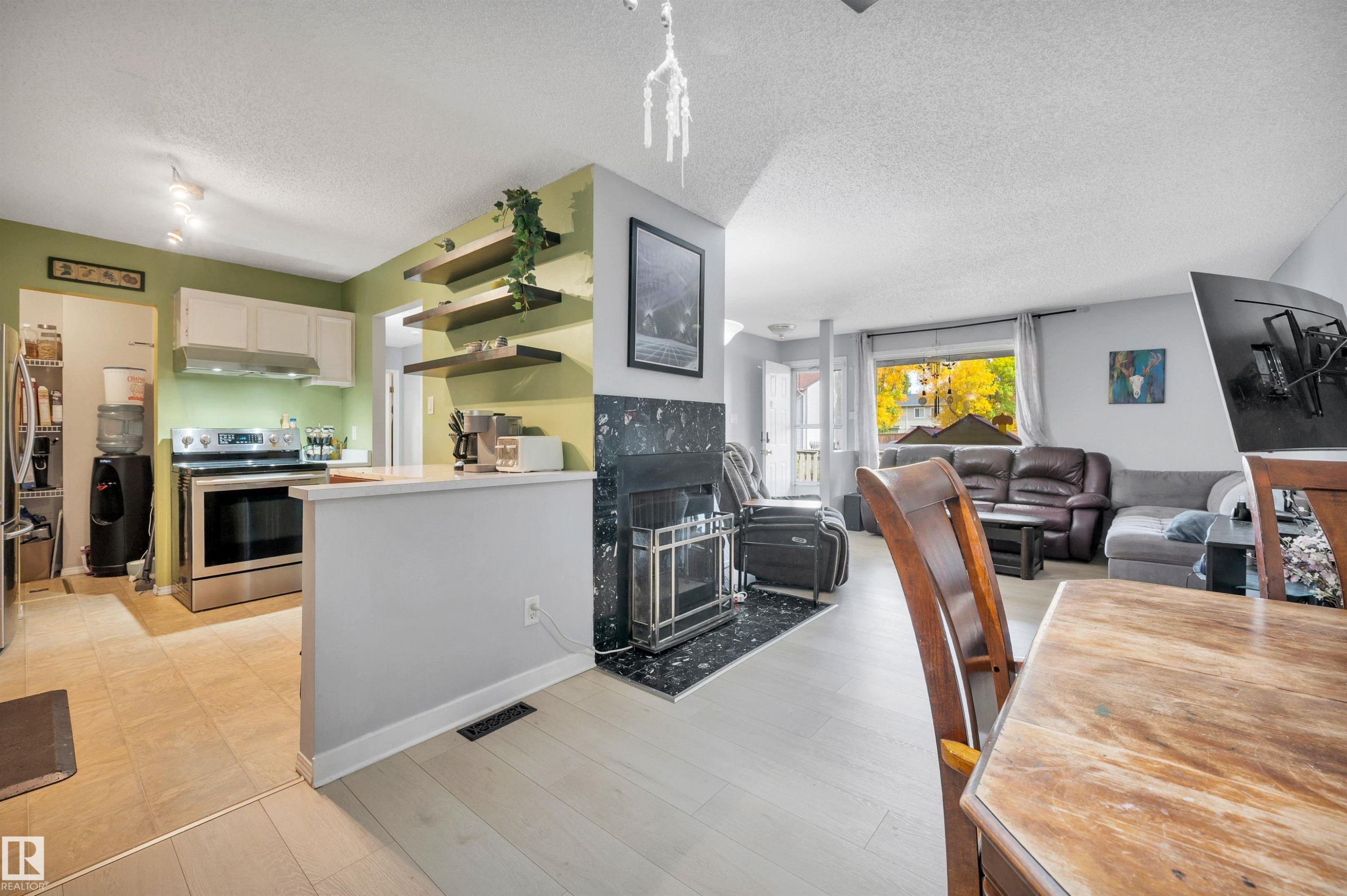 Kitchen with white cabinetry, stainless steel appliances, and tile flooring - 15017 26 Street Nw, Edmonton, AB