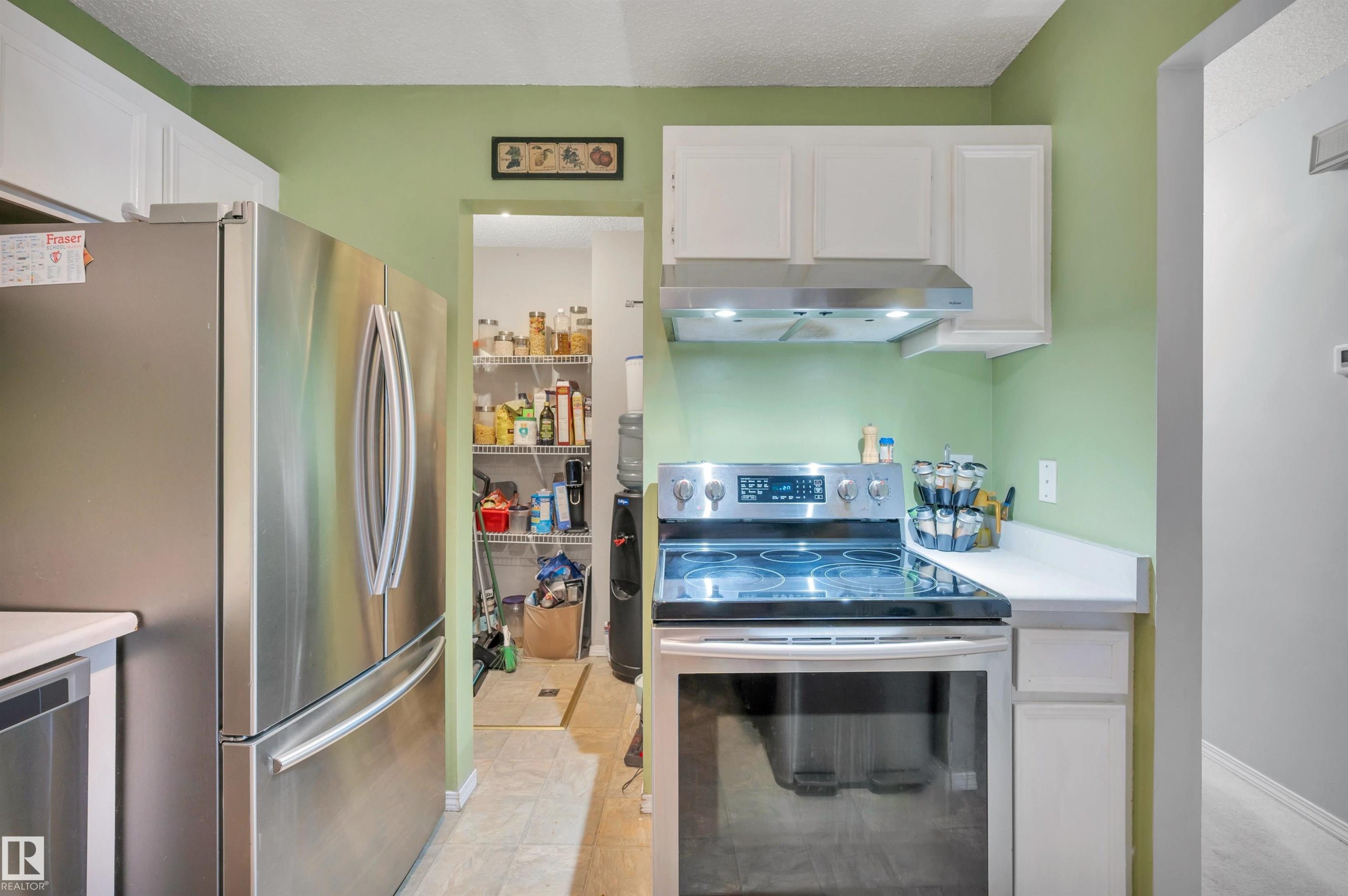 Stainless steel refrigerator, stainless steel electric range, white upper cabinetry, white countertops, and recessed lighting - 15017 26 Street Nw, Edmonton, AB