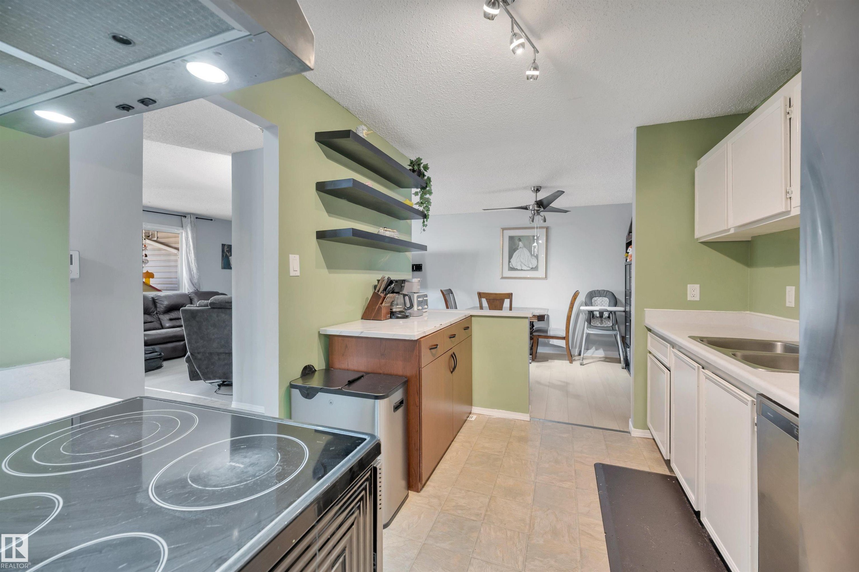 Kitchen featuring white cabinetry, light countertops, and a stainless steel sink - 15017 26 Street Nw, Edmonton, AB