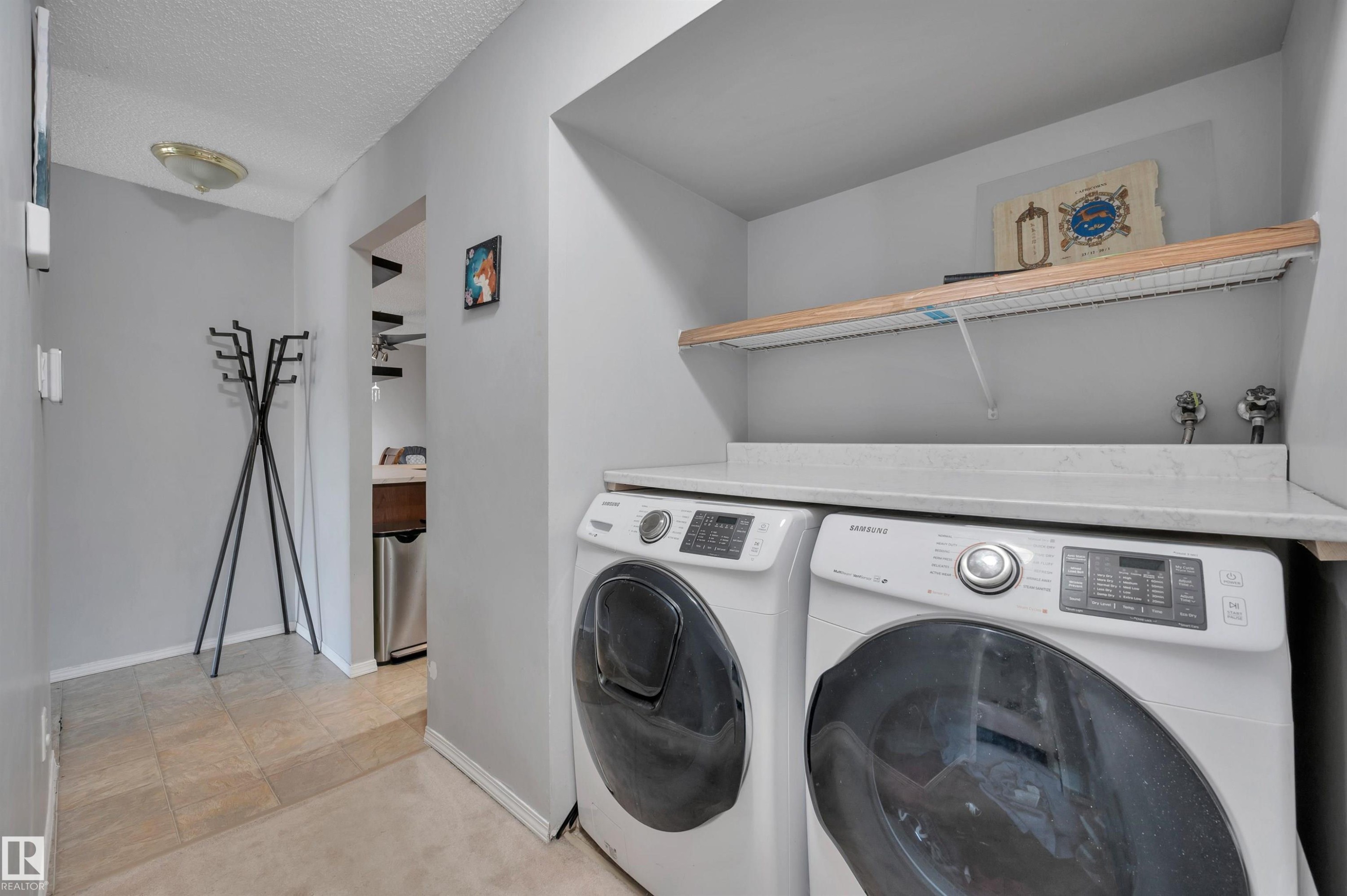 Dedicated laundry area featuring a countertop surface, overhead shelving, and neutral wall tones - 15017 26 Street Nw, Edmonton, AB