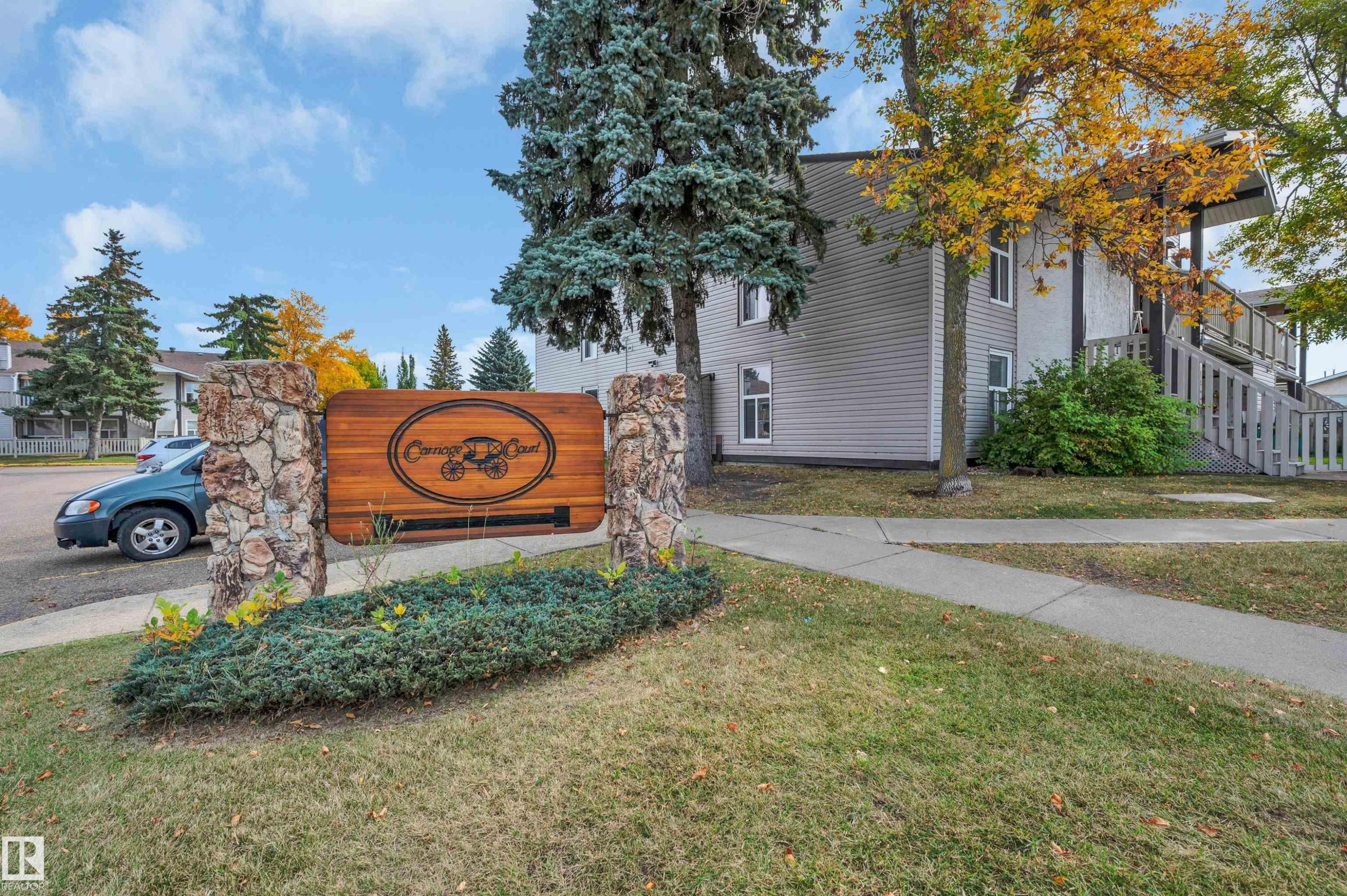 Stone-clad entryway signage with wood-finish panel - 15017 26 Street Nw, Edmonton, AB