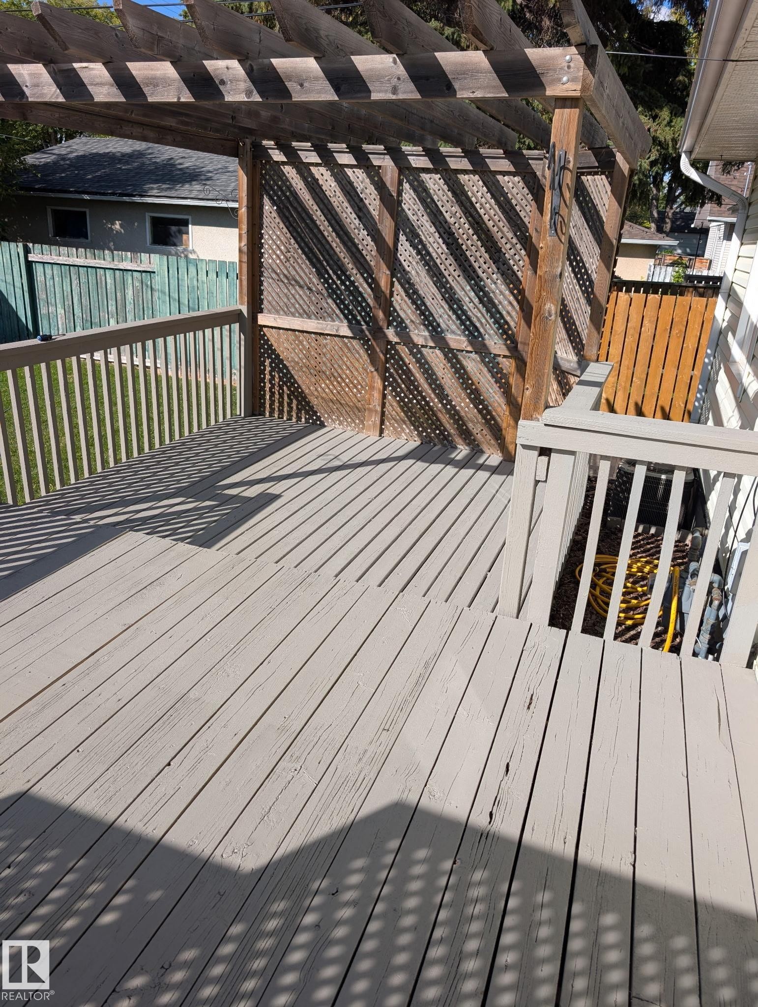 Expansive outdoor deck with a wooden pergola and privacy lattice, featuring durable decking and railing - 11836 62 Street Nw, Edmonton, AB