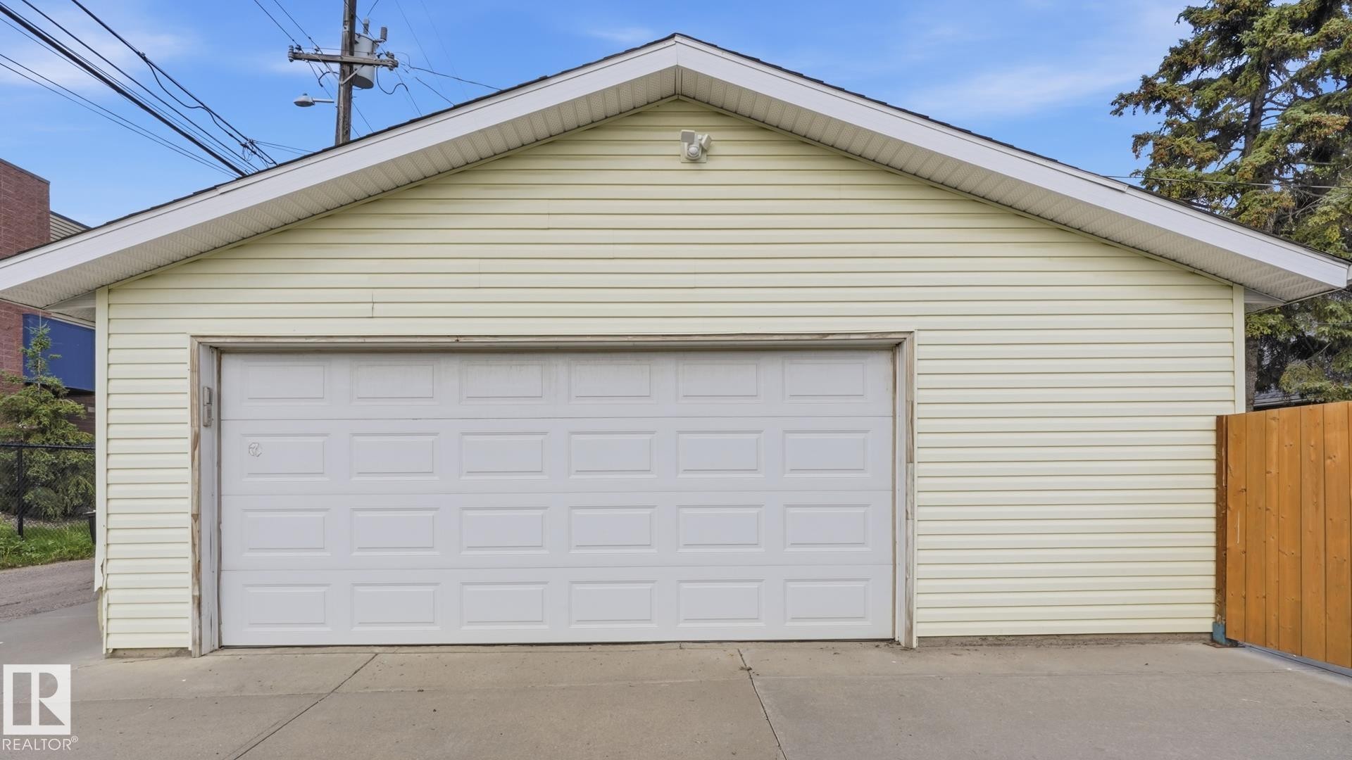 Detached garage featuring panel siding, an overhead door, and a concrete driveway - 11836 62 Street Nw, Edmonton, AB