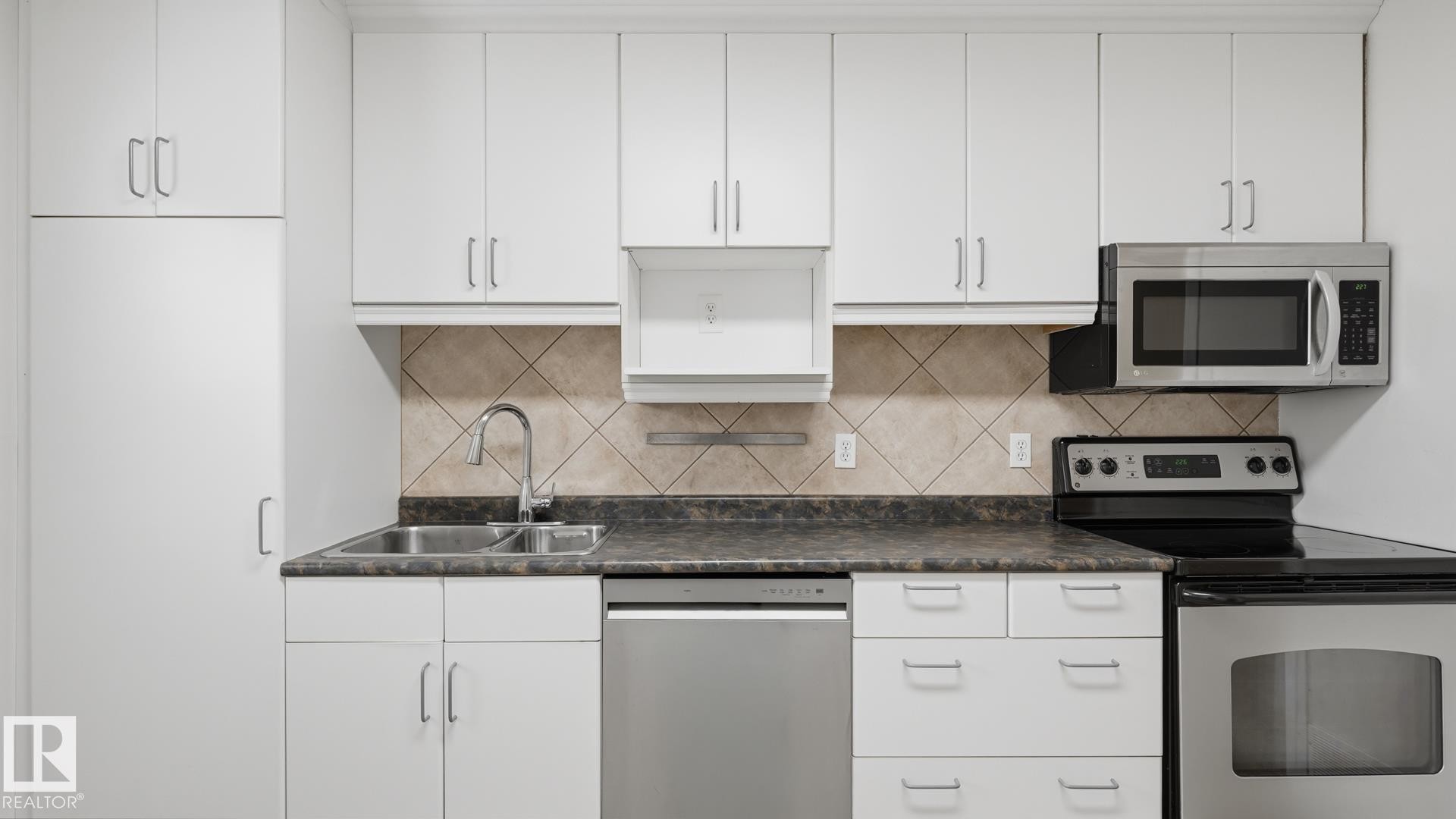 White cabinetry with stainless steel hardware, tile backsplash, and dark countertops - 11836 62 Street Nw, Edmonton, AB