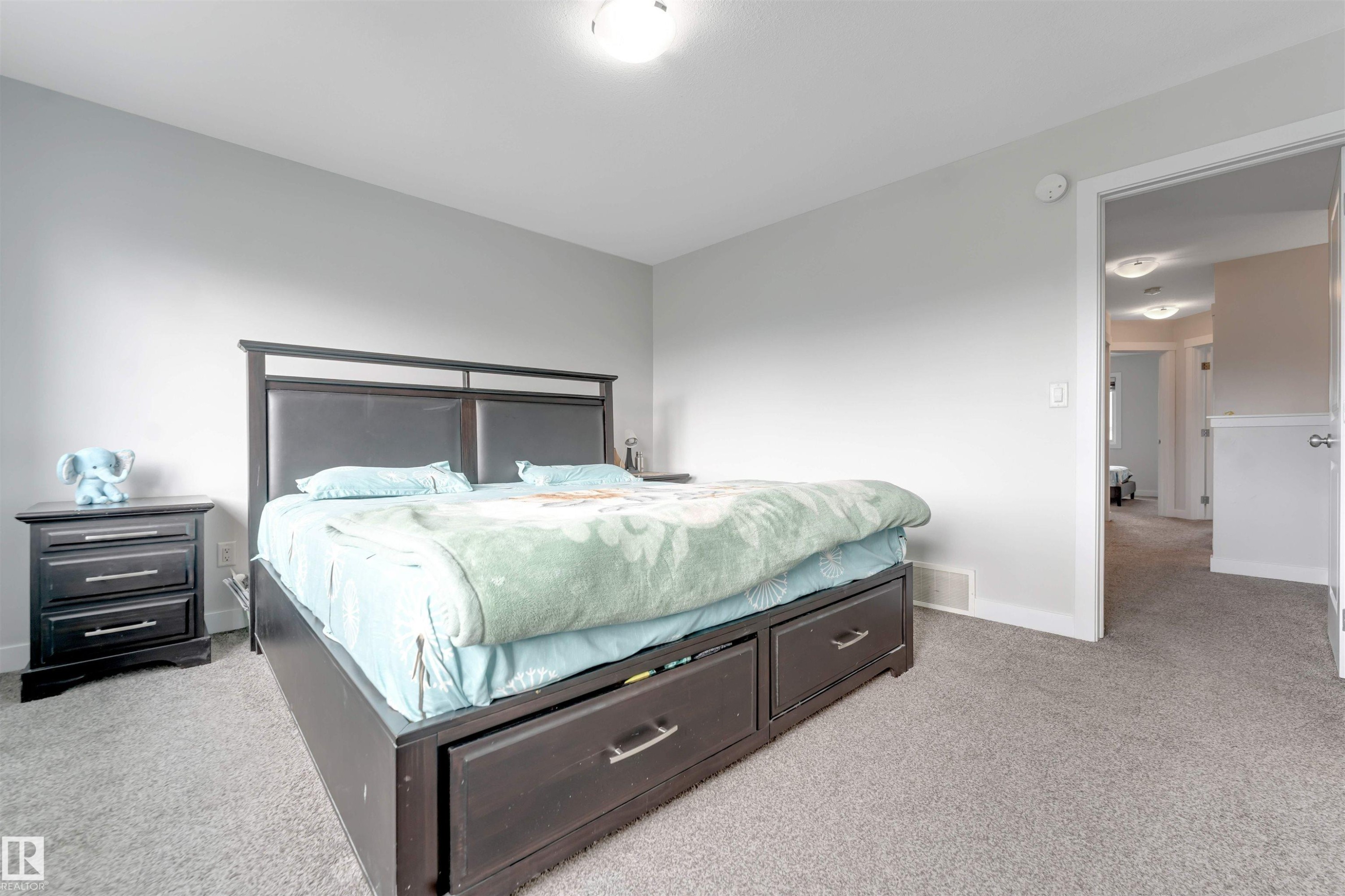 Wall-to-wall carpeting in a neutral tone, light gray wall paint, and a white ceiling with a flush-mount light fixture - 2004 15 Avenue Nw, Edmonton, AB