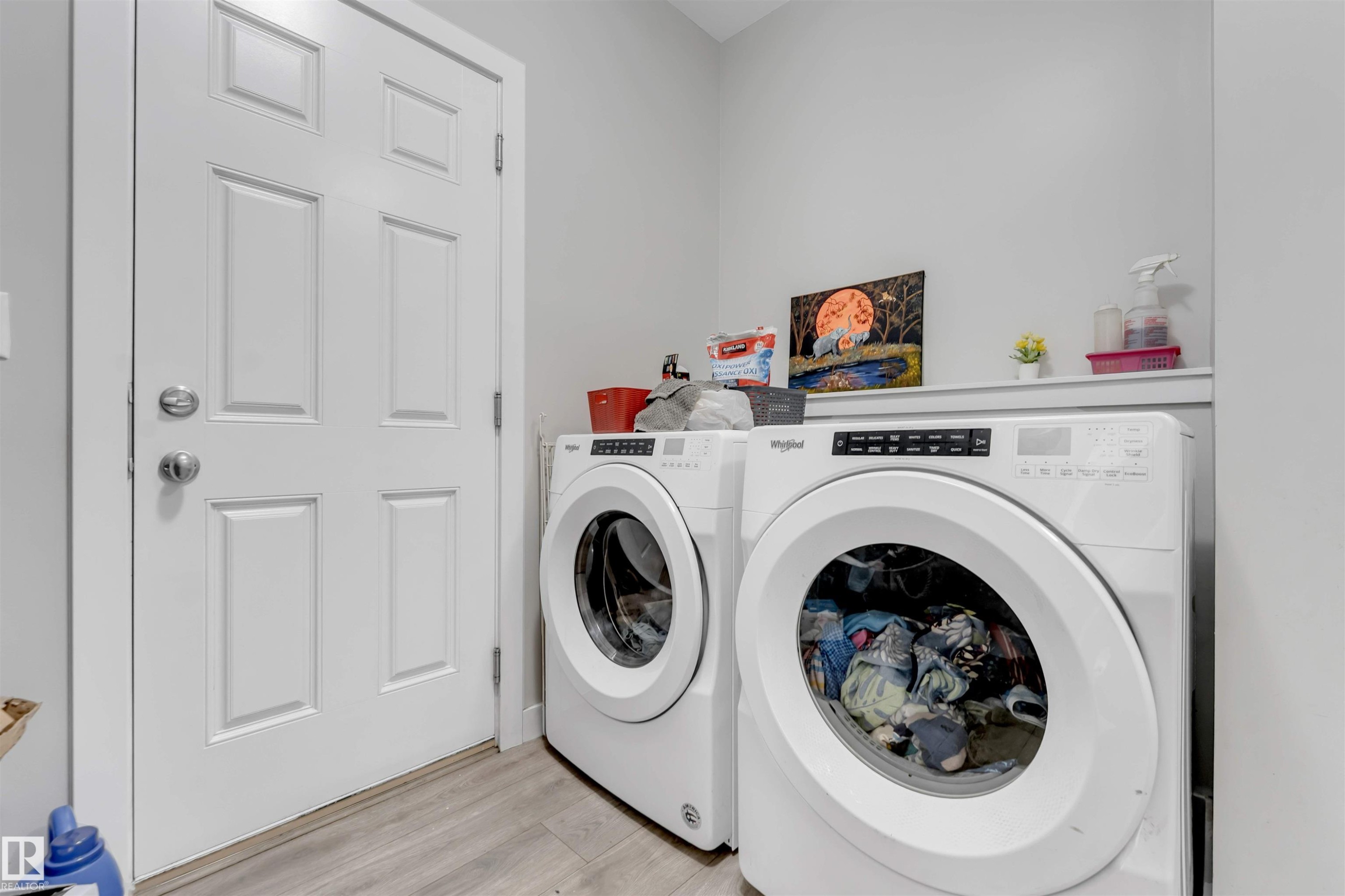 Dedicated laundry space featuring a built-in shelf, light-toned walls, and wood-finish flooring - 2004 15 Avenue Nw, Edmonton, AB