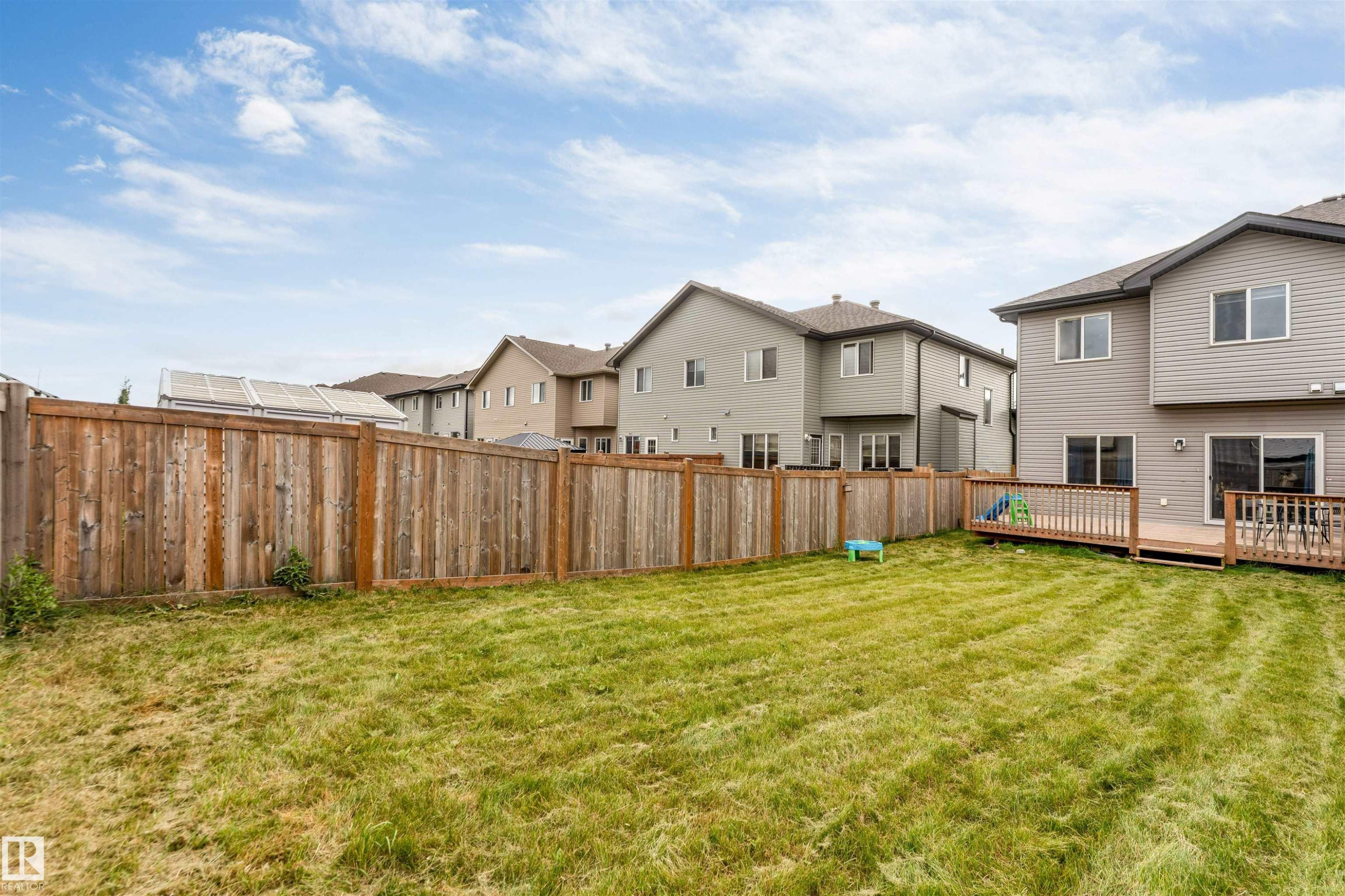 Expansive grassy yard with a full privacy fence and a wood-finish deck featuring a wood-finish railing - 2004 15 Avenue Nw, Edmonton, AB