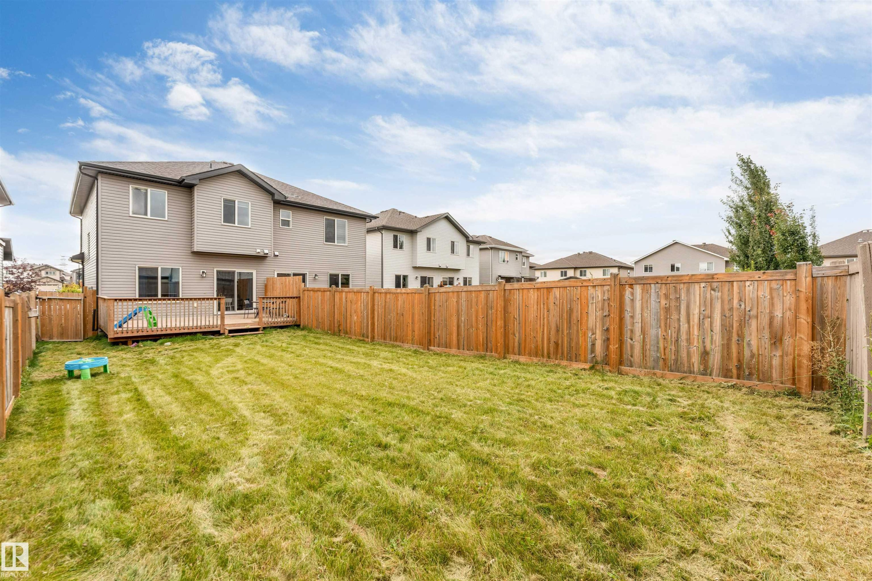 Expansive fenced backyard with a wood deck and sliding glass door access - 2004 15 Avenue Nw, Edmonton, AB