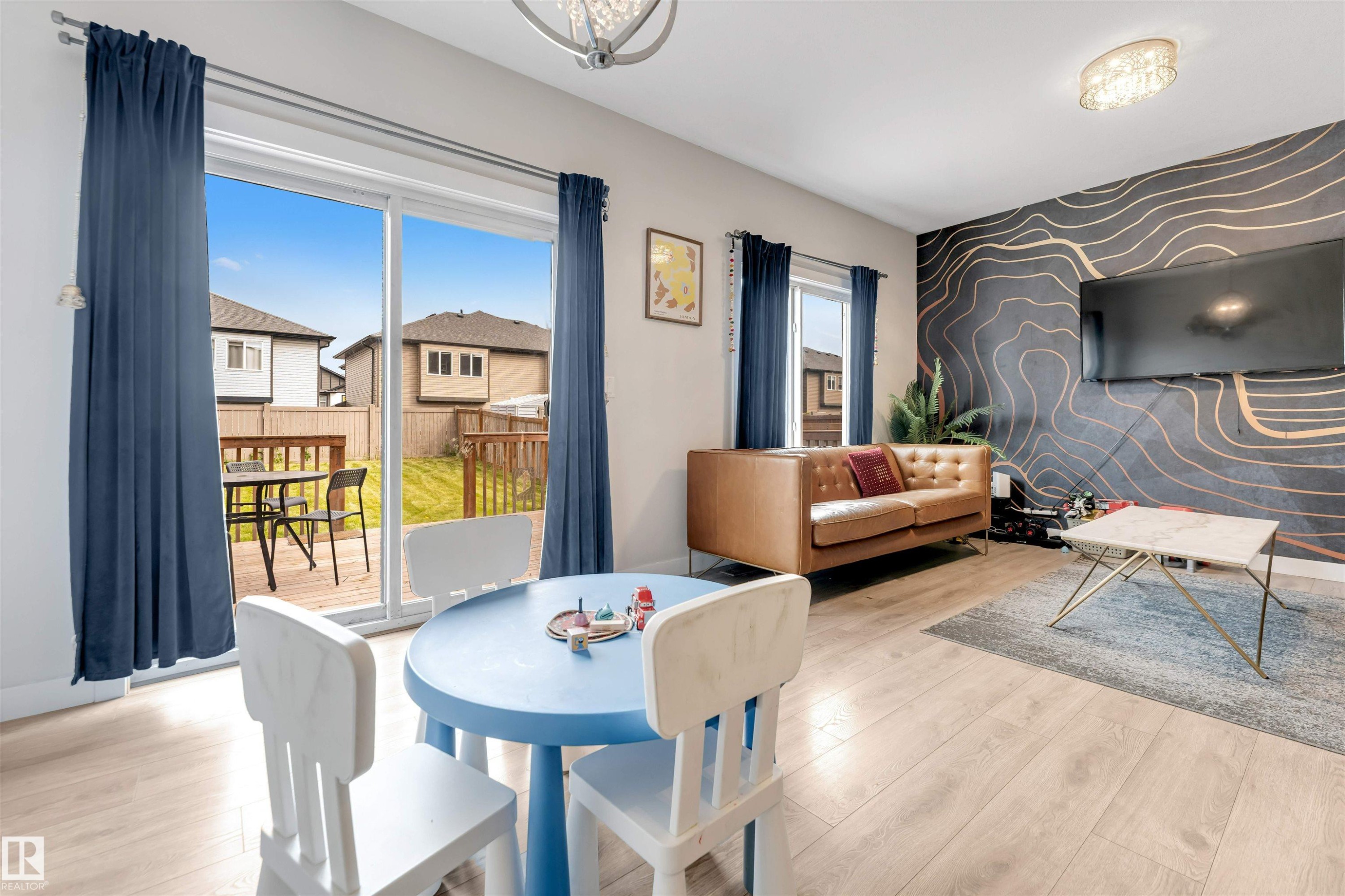 Wood-finish flooring, accent wall with a geometric pattern, ceiling-mounted light fixture, sliding glass doors, and an exterior wood deck - 2004 15 Avenue Nw, Edmonton, AB
