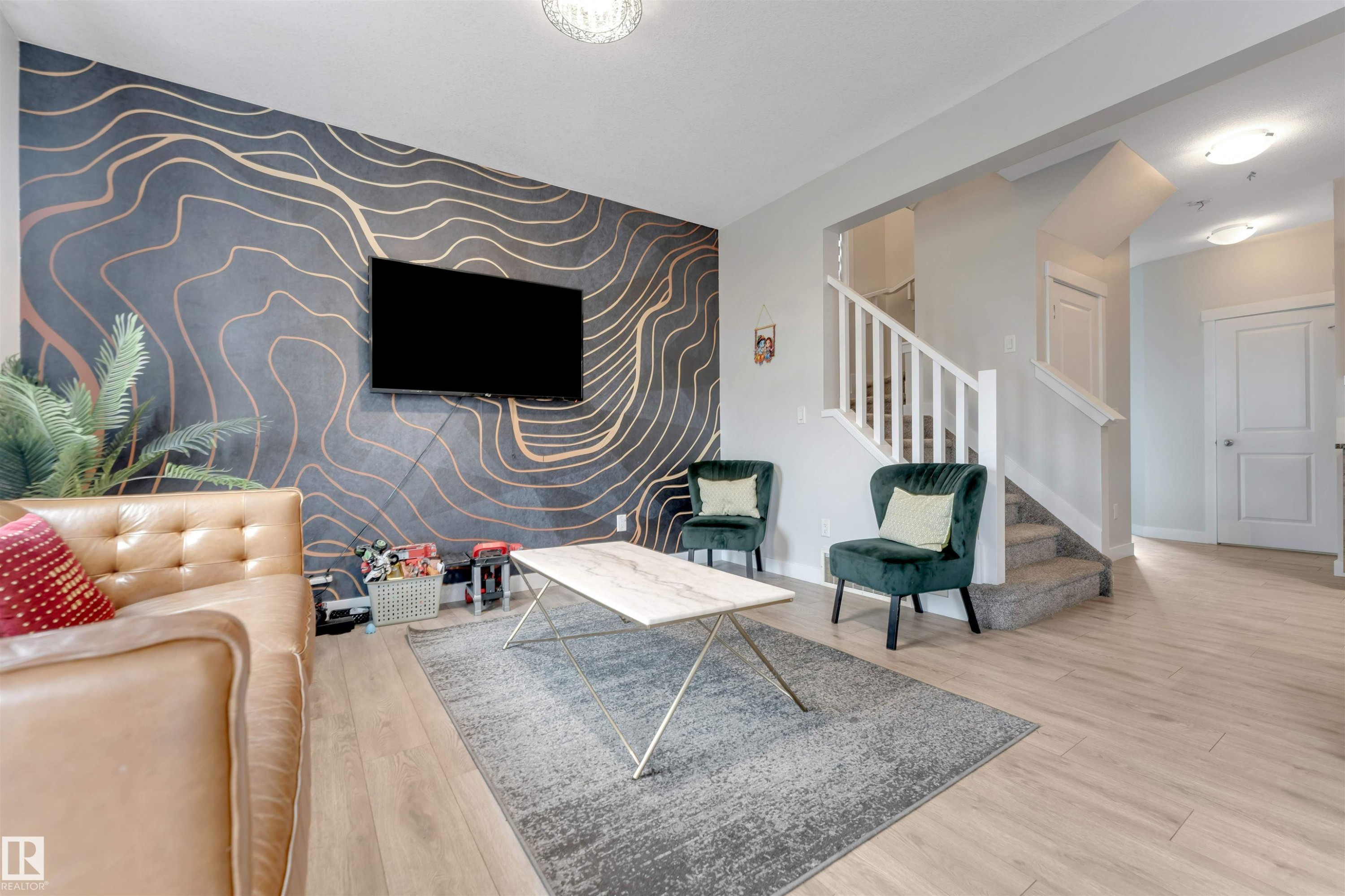 Accent wall with a modern abstract design, light wood-finish flooring, staircase with white risers and handrail, ceiling-mounted lighting fixtures, and solid panel interior doors - 2004 15 Avenue Nw, Edmonton, AB
