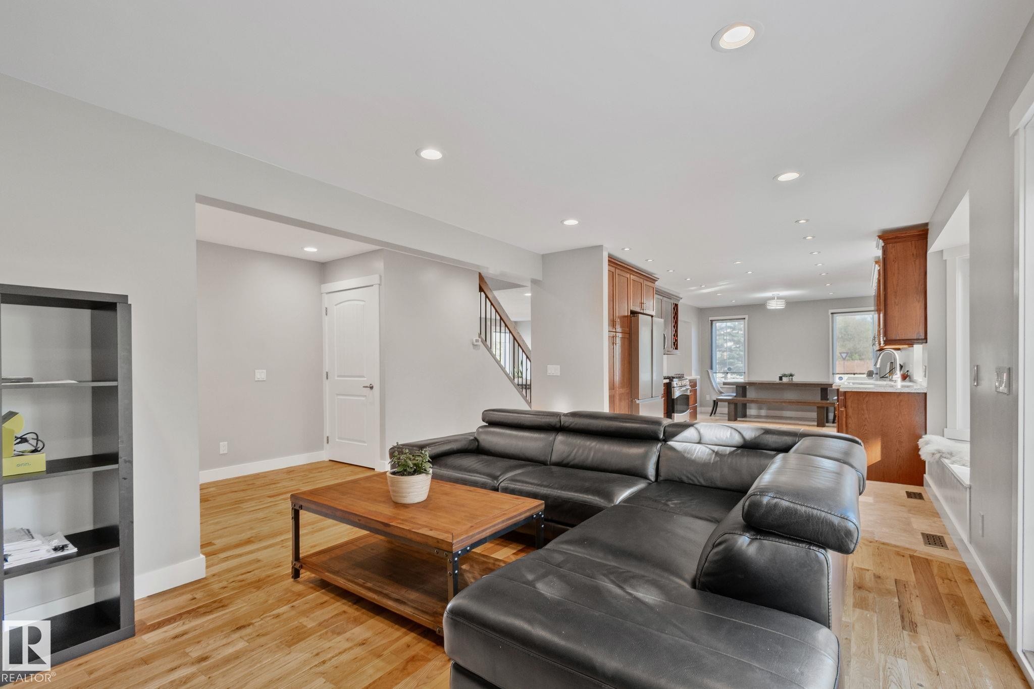 Open-concept living space featuring wood-finish flooring, recessed lighting, and a staircase with wood treads and a metal railing - 12403 29A Avenue Nw, Edmonton, AB
