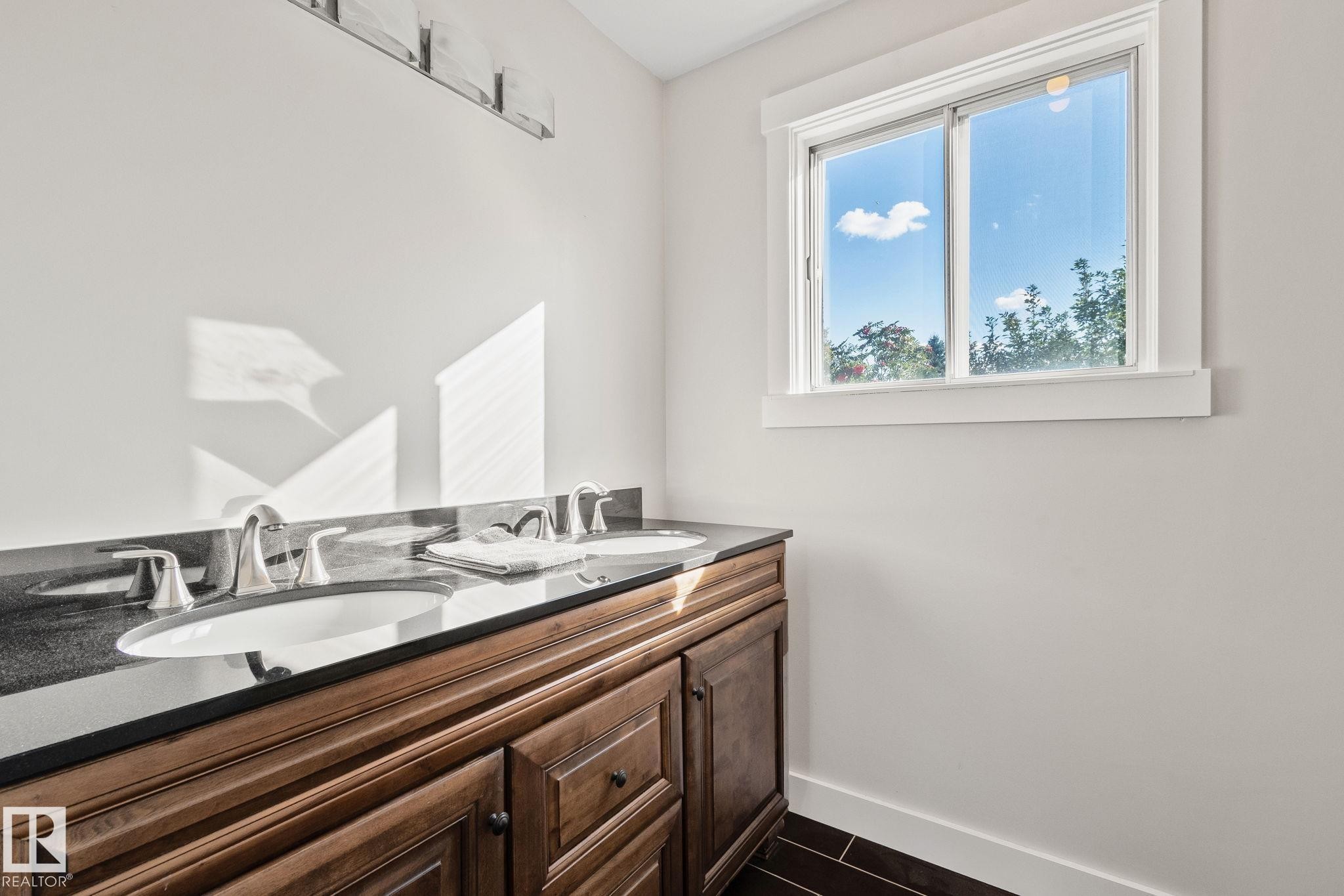 Dual vanity with inset wood-finish cabinetry, undermount sinks, and a dark countertop - 12403 29A Avenue Nw, Edmonton, AB