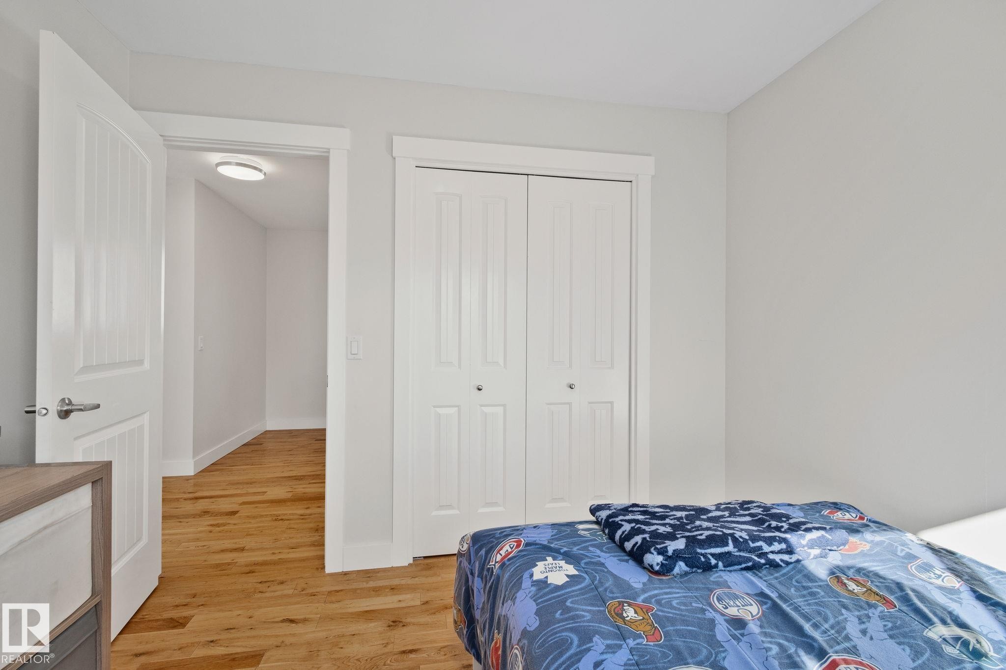 Wood-finish flooring, white paneled interior doors, and white bi-fold closet doors - 12403 29A Avenue Nw, Edmonton, AB