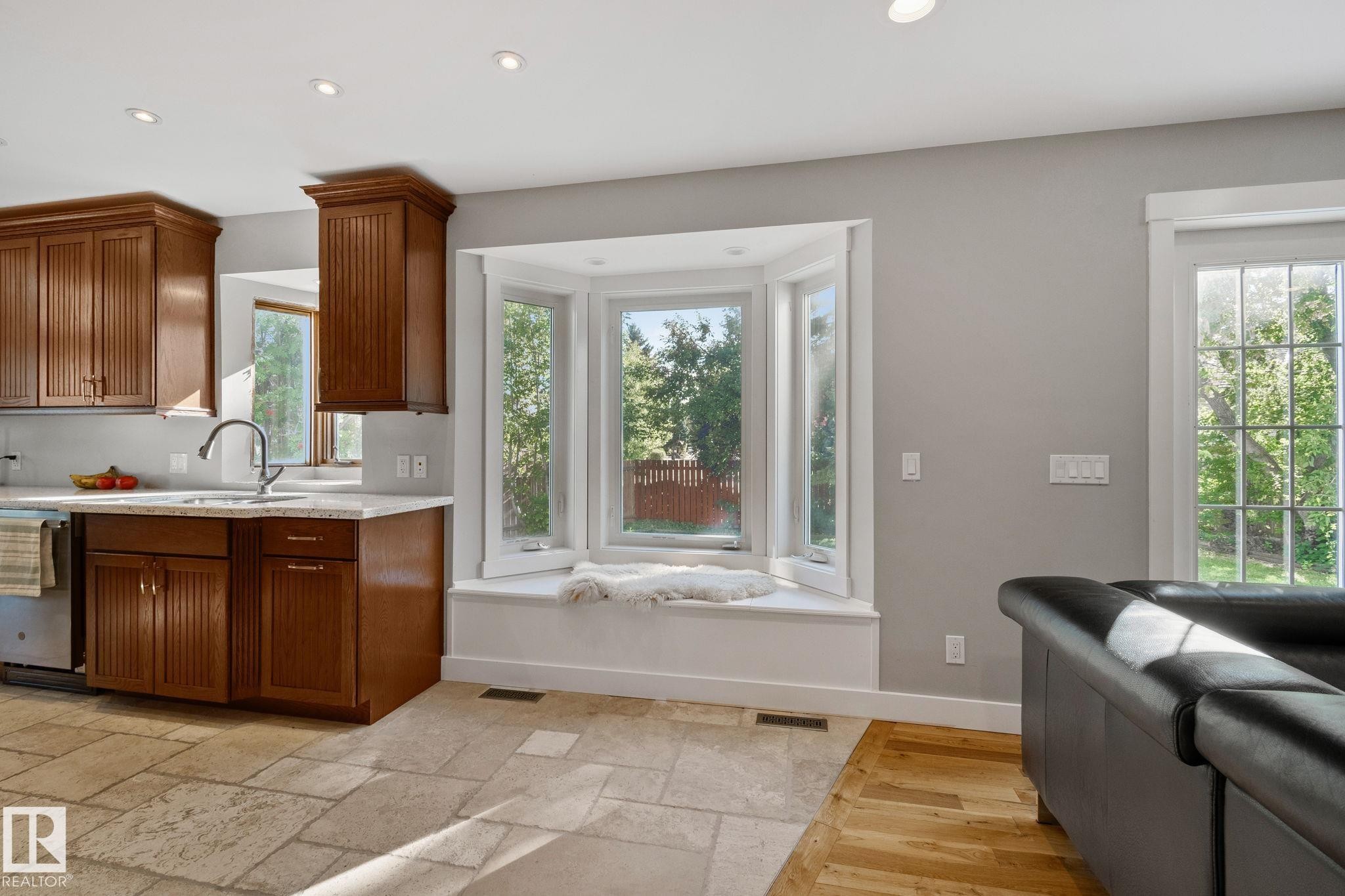 Recessed lighting throughout, wood-finish cabinetry, light-toned countertop, bay window, and a door with multiple window panes - 12403 29A Avenue Nw, Edmonton, AB