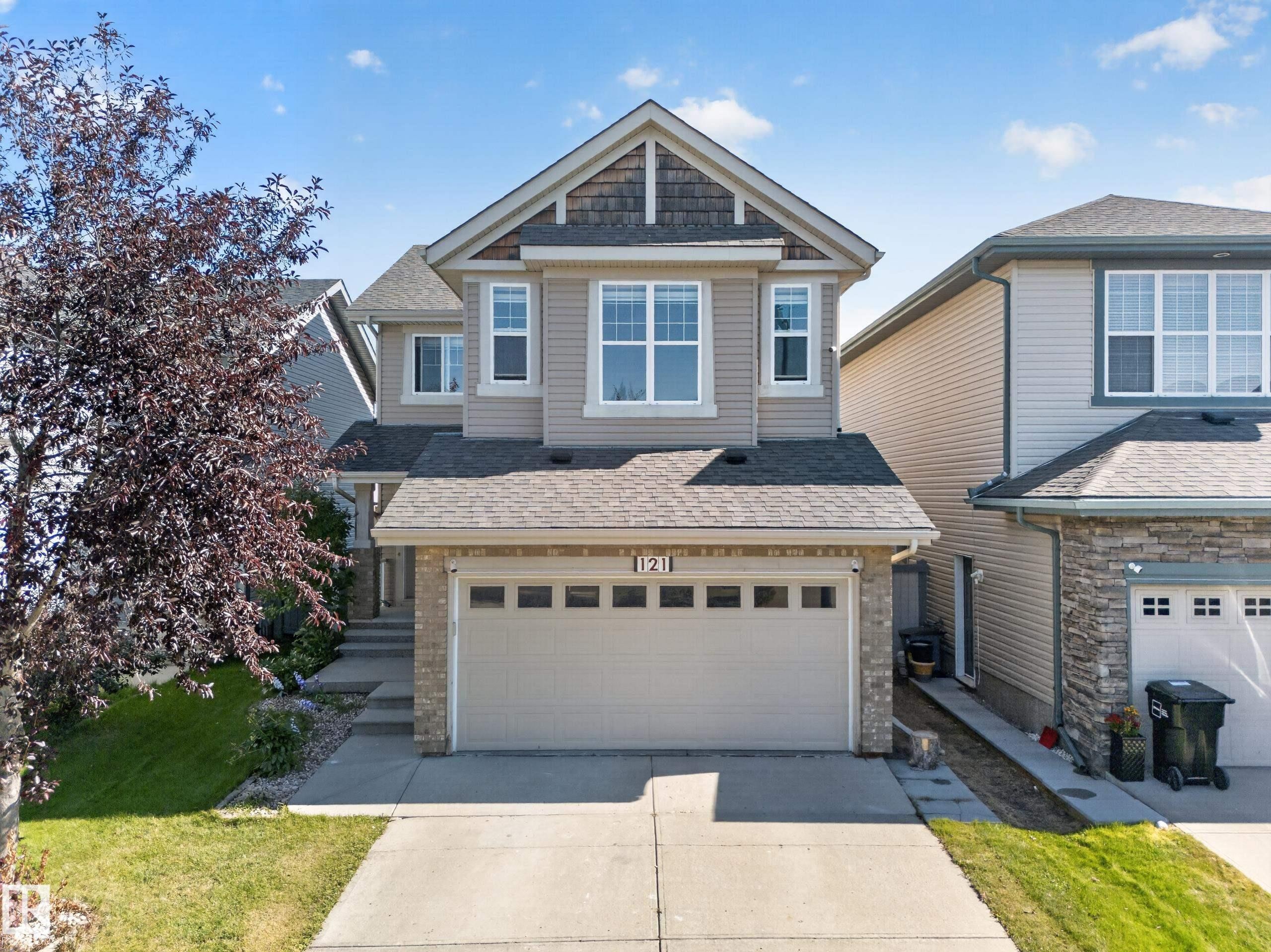 Two-story exterior with a gabled roof, stone accents, attached two-car garage, and concrete driveway - 121 64 Street Sw, Edmonton, AB