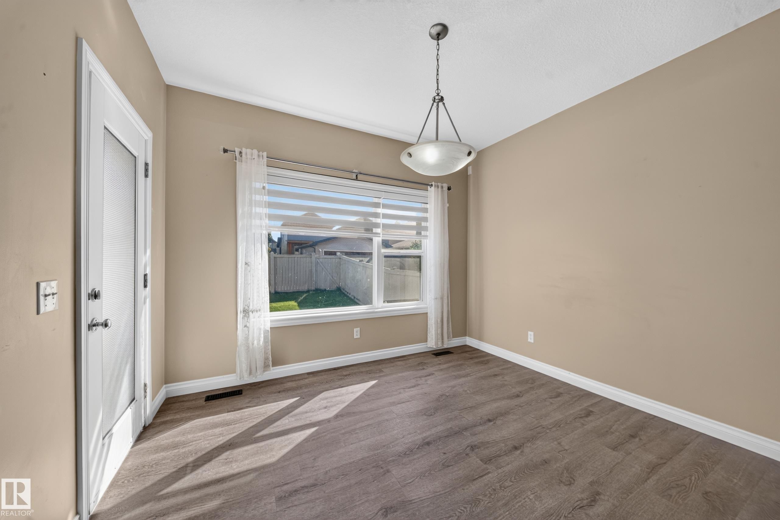 Wood-finish flooring, white trim, and a contemporary ceiling fixture - 121 64 Street Sw, Edmonton, AB