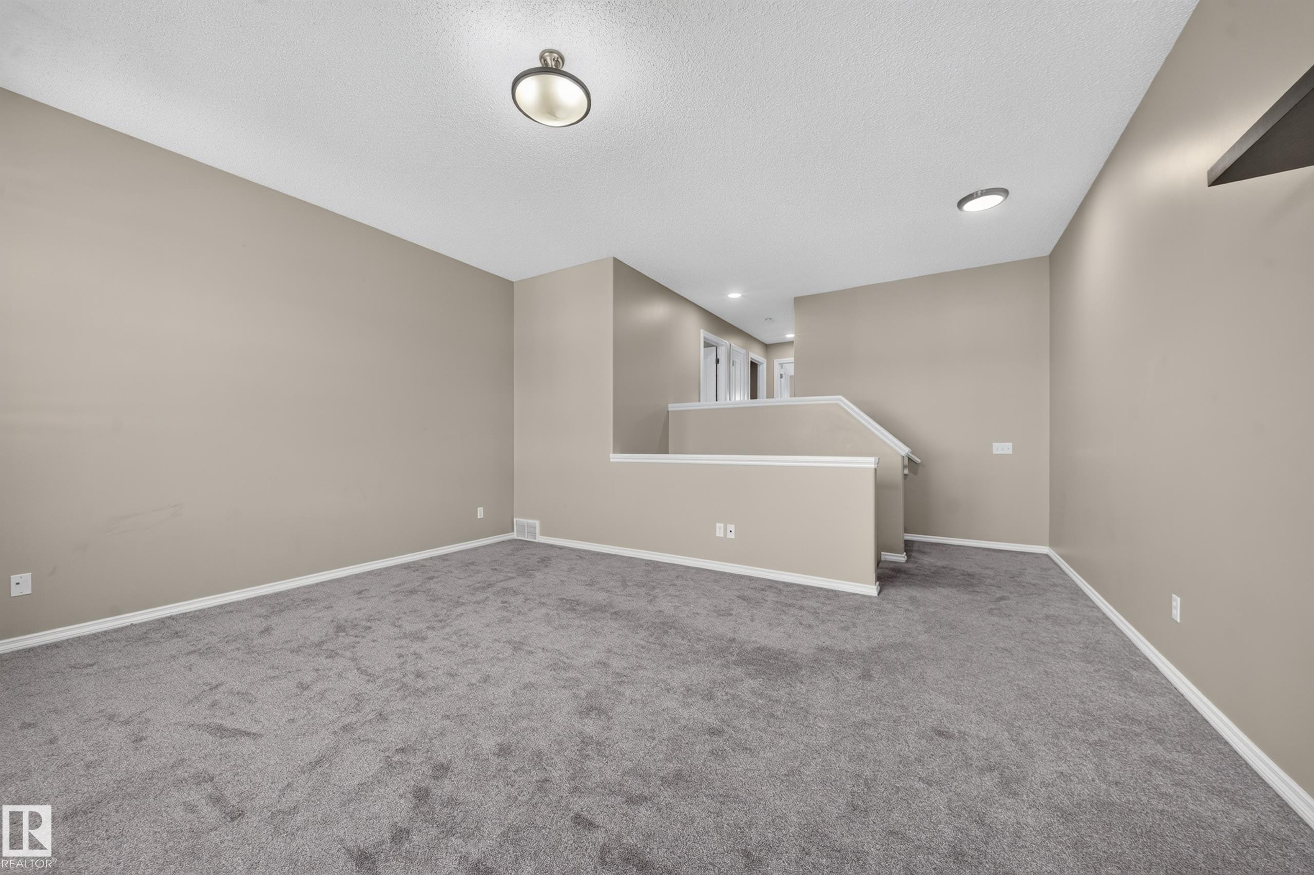 Spacious room featuring neutral painted walls, gray carpet flooring, and white trim - 121 64 Street Sw, Edmonton, AB