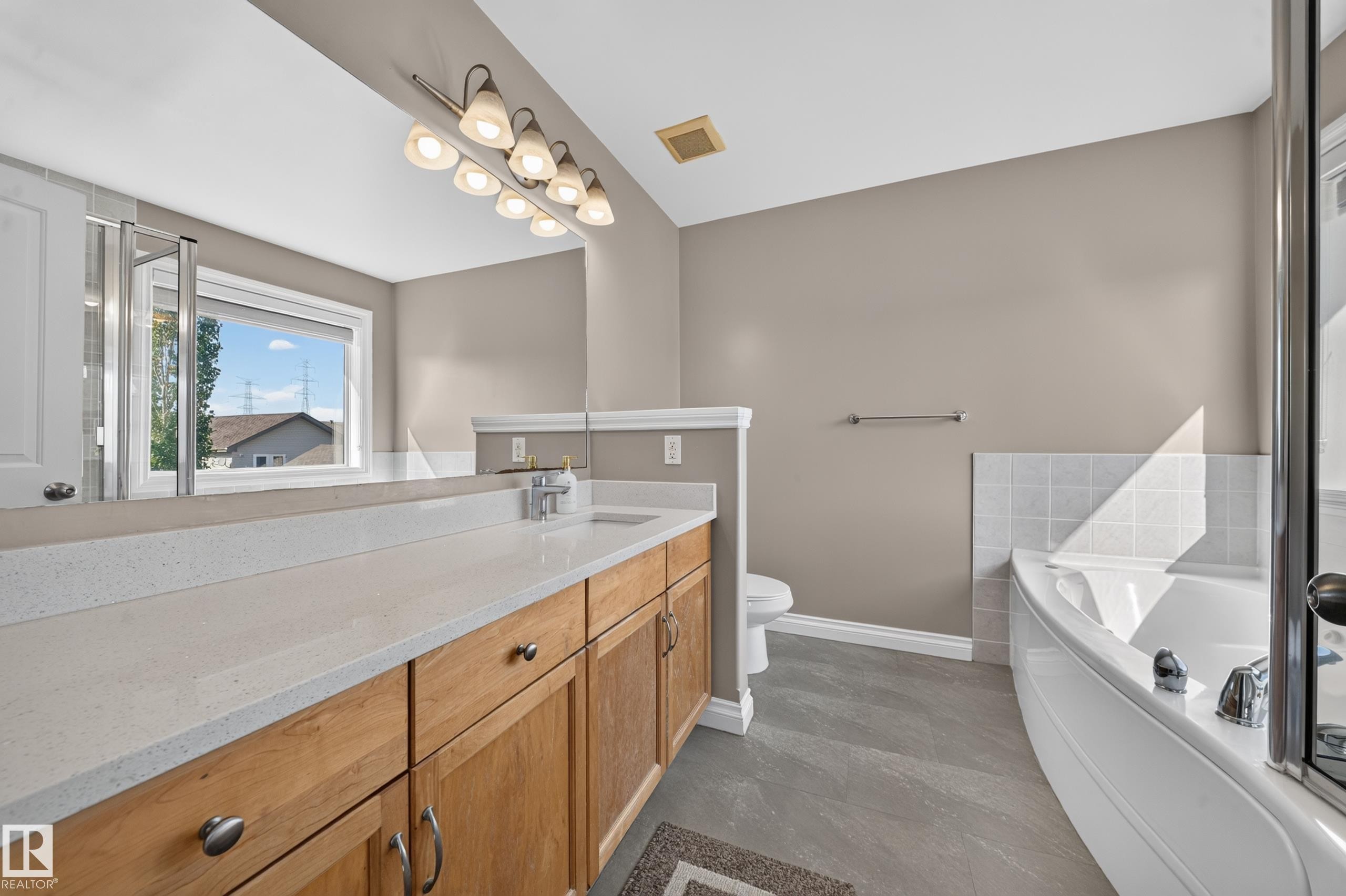 Dual vanity with light-toned countertops and natural wood cabinetry - 121 64 Street Sw, Edmonton, AB