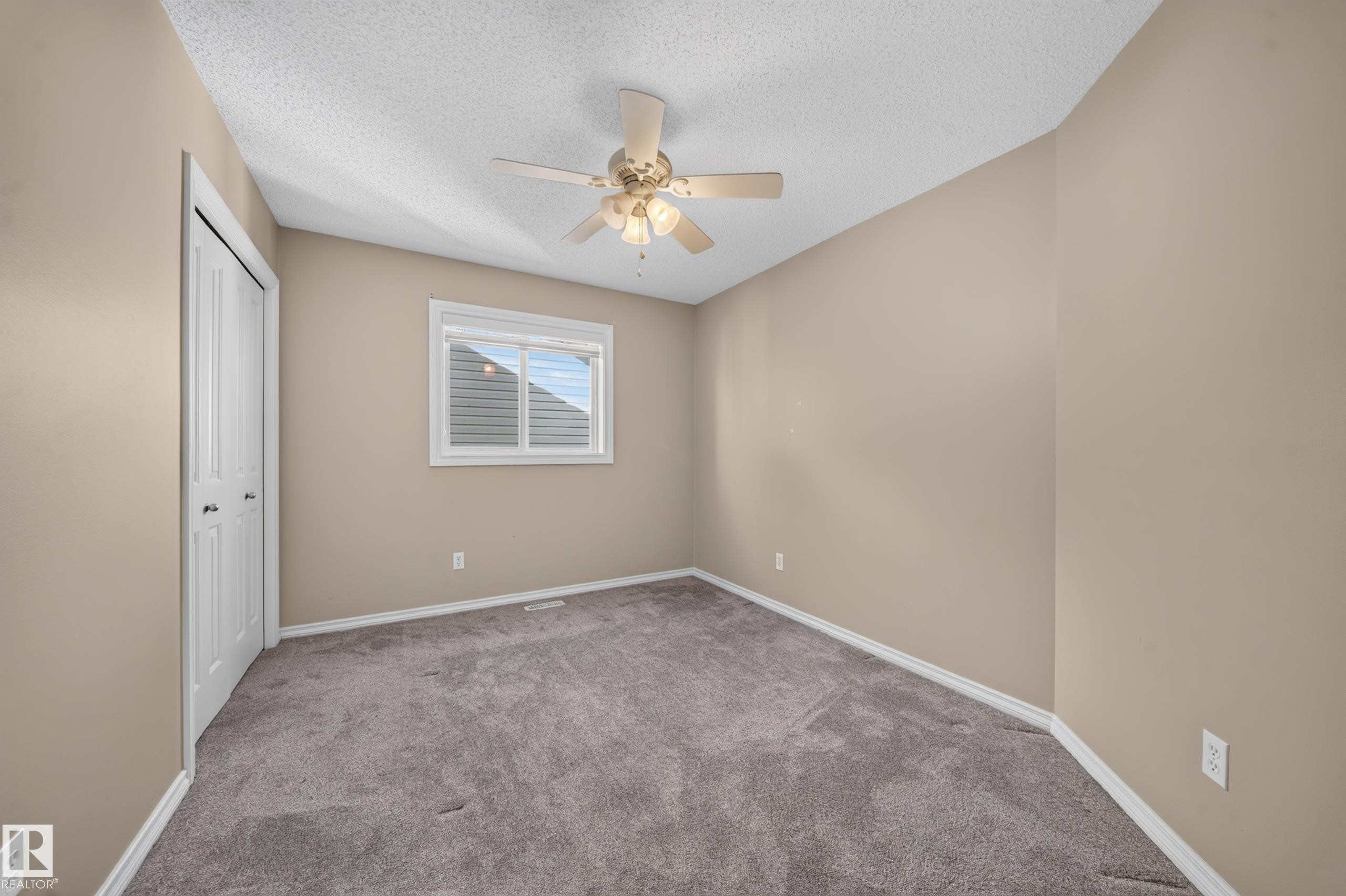 Vaulted ceiling with a ceiling fan, neutral wall paint, white trim, gray carpet, and a window with blinds - 121 64 Street Sw, Edmonton, AB