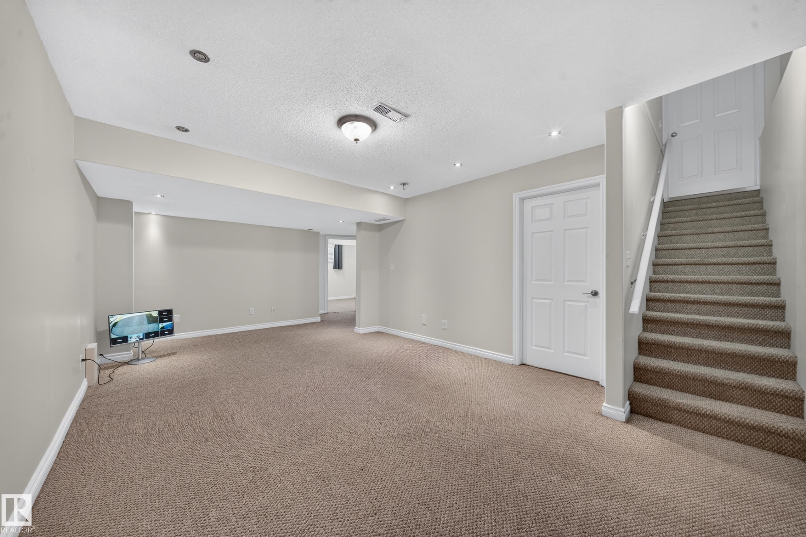 Carpeted flooring, recessed lighting, white trim, paneled interior door, and a staircase with a handrail - 121 64 Street Sw, Edmonton, AB