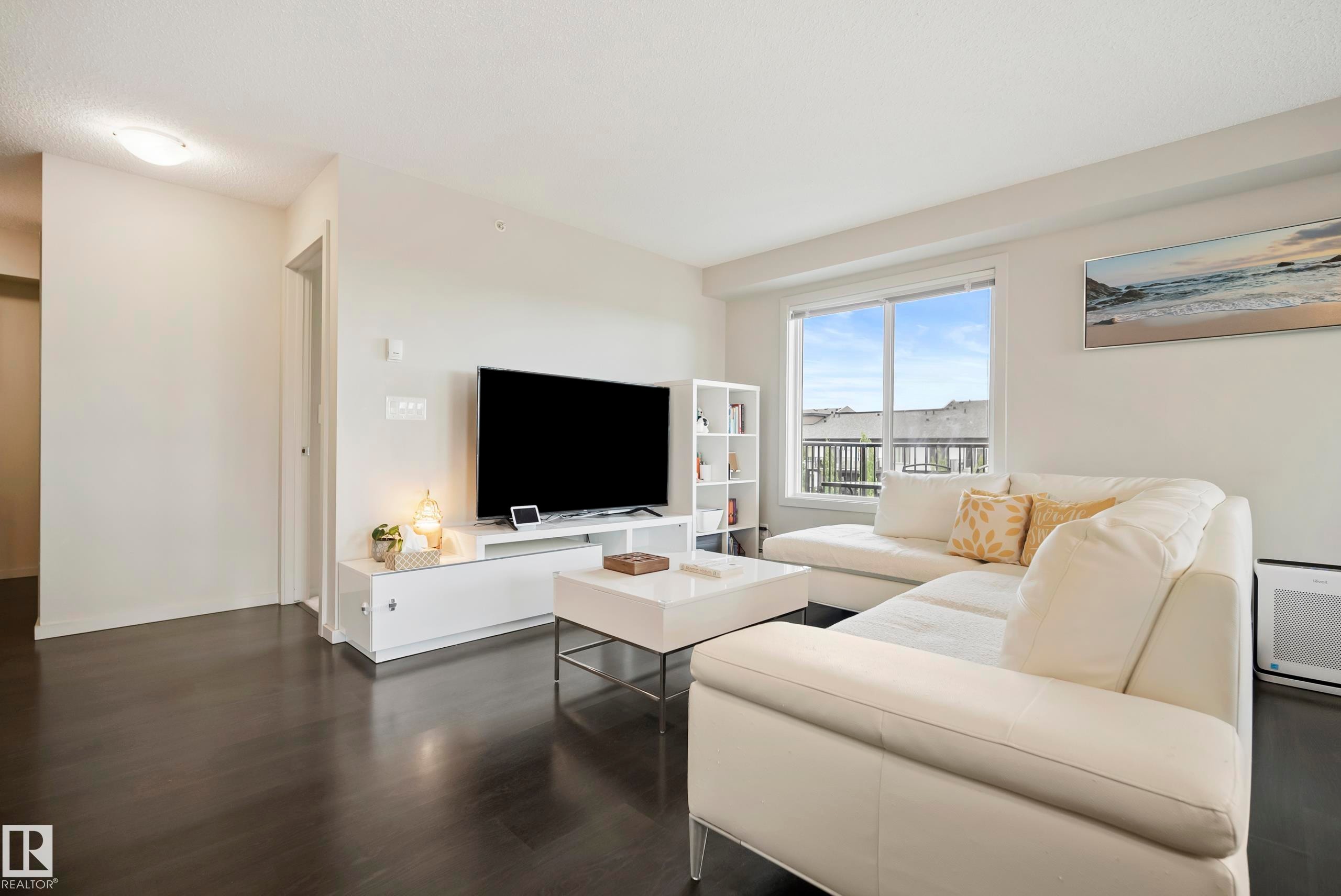 Dark wood-finish flooring with light wall tones and a window with a partial exterior building element - #419 5515 7 Av Sw, Edmonton, AB